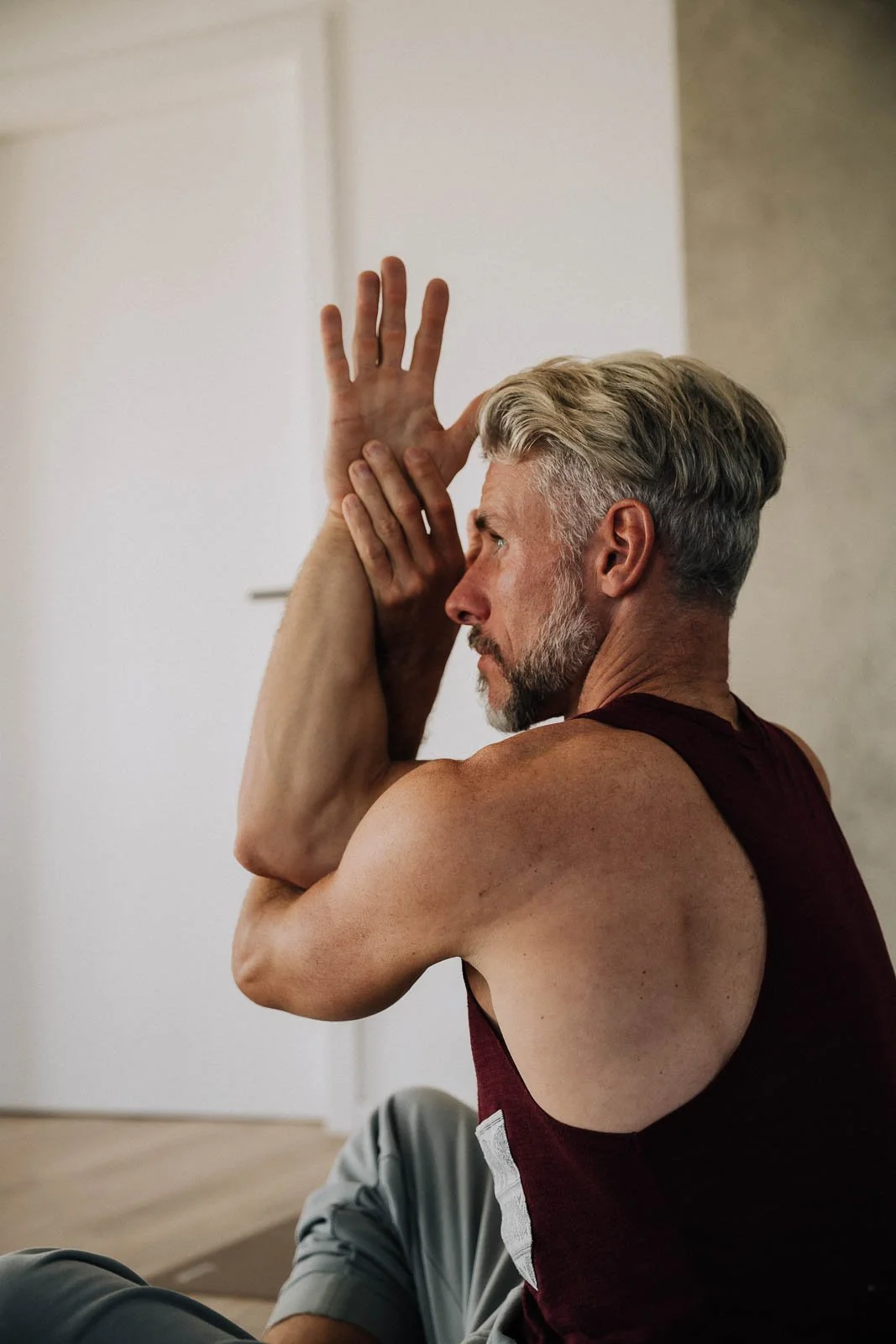 Ein sportlicher Mann macht Dehnübungen in einem Raum.