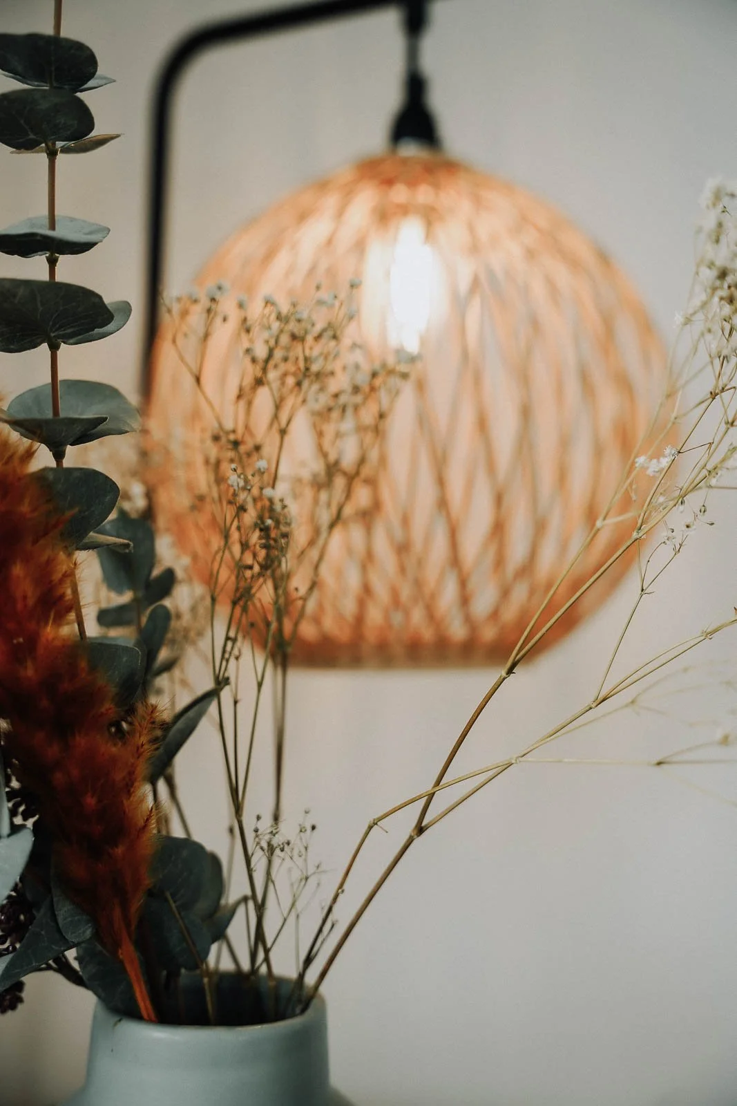 Blumen in einer Vase vor einer Wandlampe