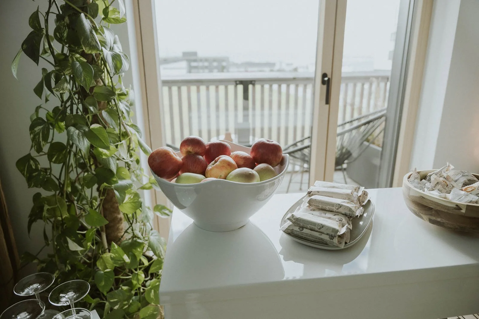 Schale mit Äpfeln auf einem weißen Tisch vor einem Fenster mit Balkonsauna