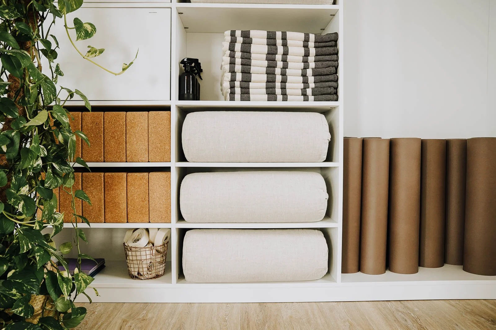 Regal mit Decken, Yogamatten, Korkblöcke und Dekorationsartikeln.