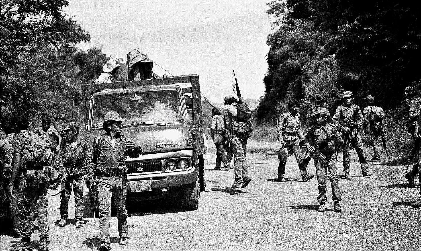 MIDAIR DISMOUNT  —  young guerrillas unloading from back of truck, road to La Palma