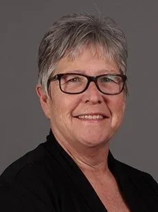 Smiling woman with short grey hair and glasses