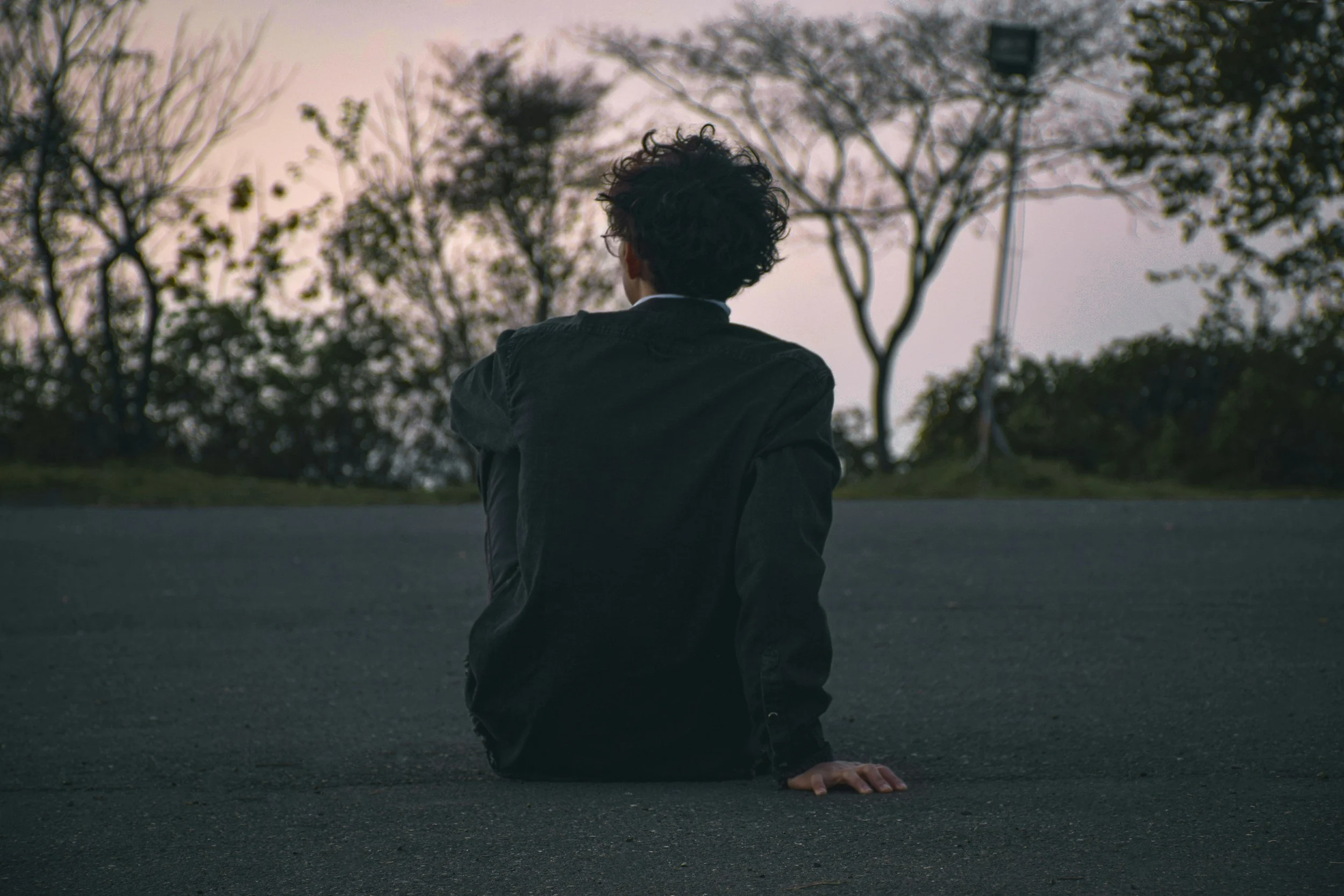 Person from the back, sitting on the ground, looking at distance