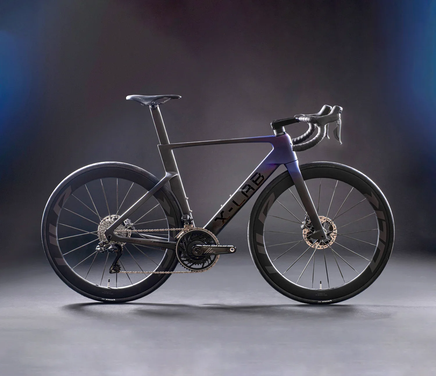 A sleek, modern black and gray road bicycle with disc brakes and deep-dish aerodynamic wheels, set against a dark background with subtle lighting.