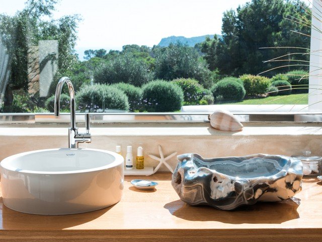 Bathroom countertop with a sink, ocean-themed soap dish, and scenic view of trees and mountains through window