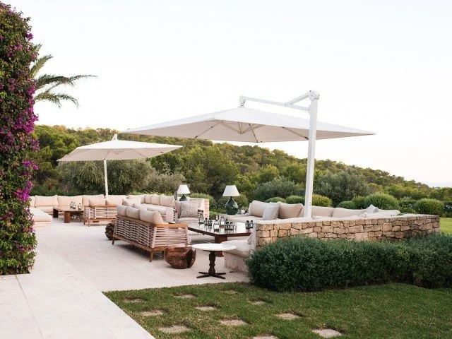 Outdoor patio with lounge seating, umbrellas, and a view of greenery and hills in the background.