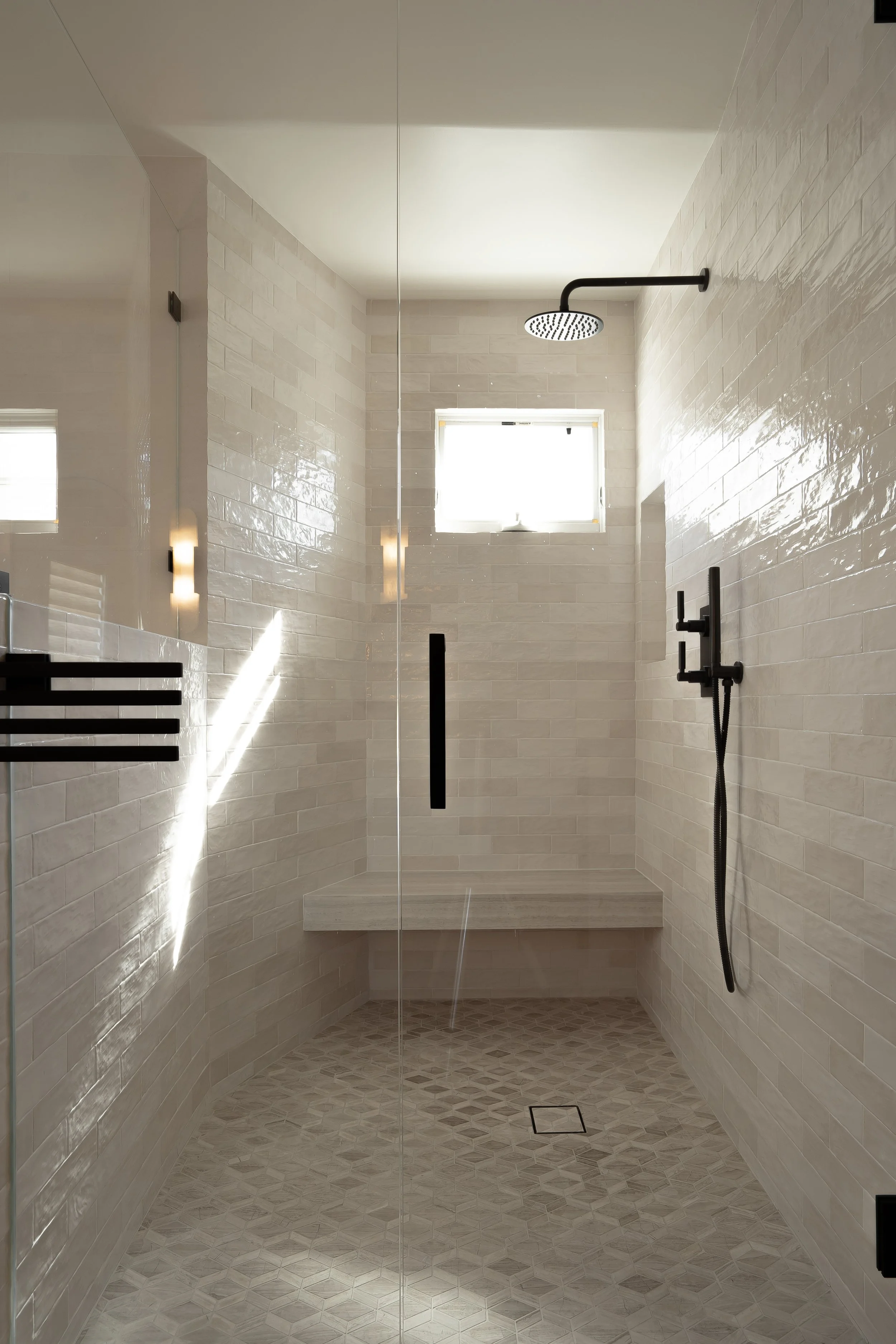 Modern tiled shower with a rain shower head, small window, and built-in bench.