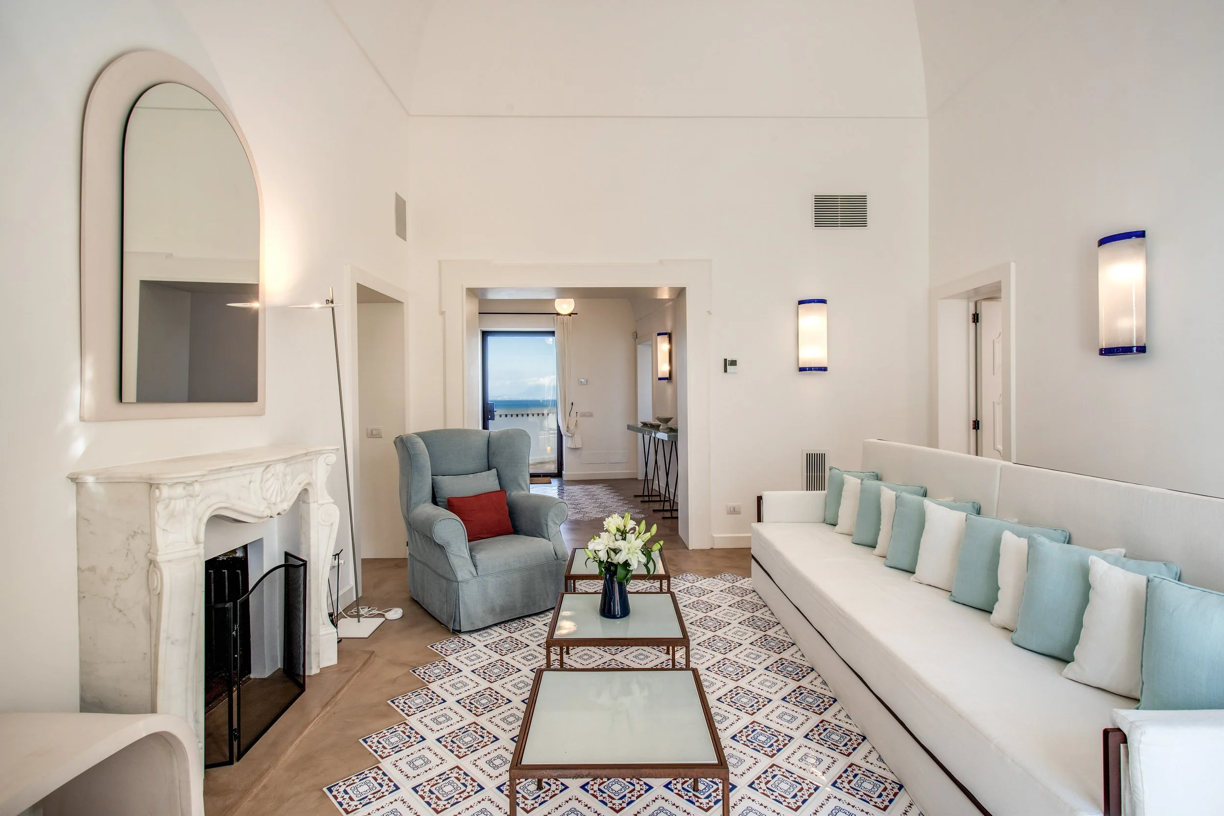 Spacious living room with fireplace, white sofa, and plush blue chair in Villa Nadiana.
