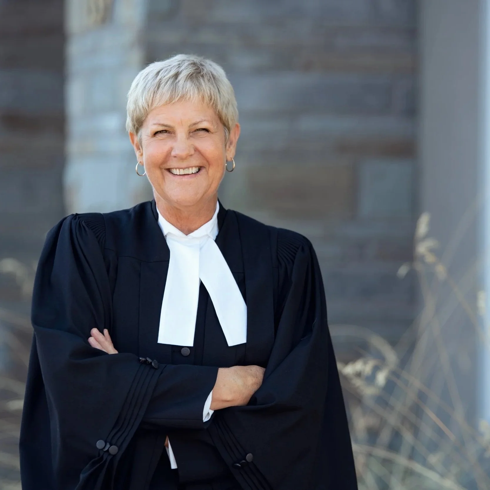 Elderly woman in judicial robes smiling outside