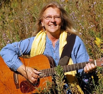 Patty Kakac holds her guitar and smiles for the camera