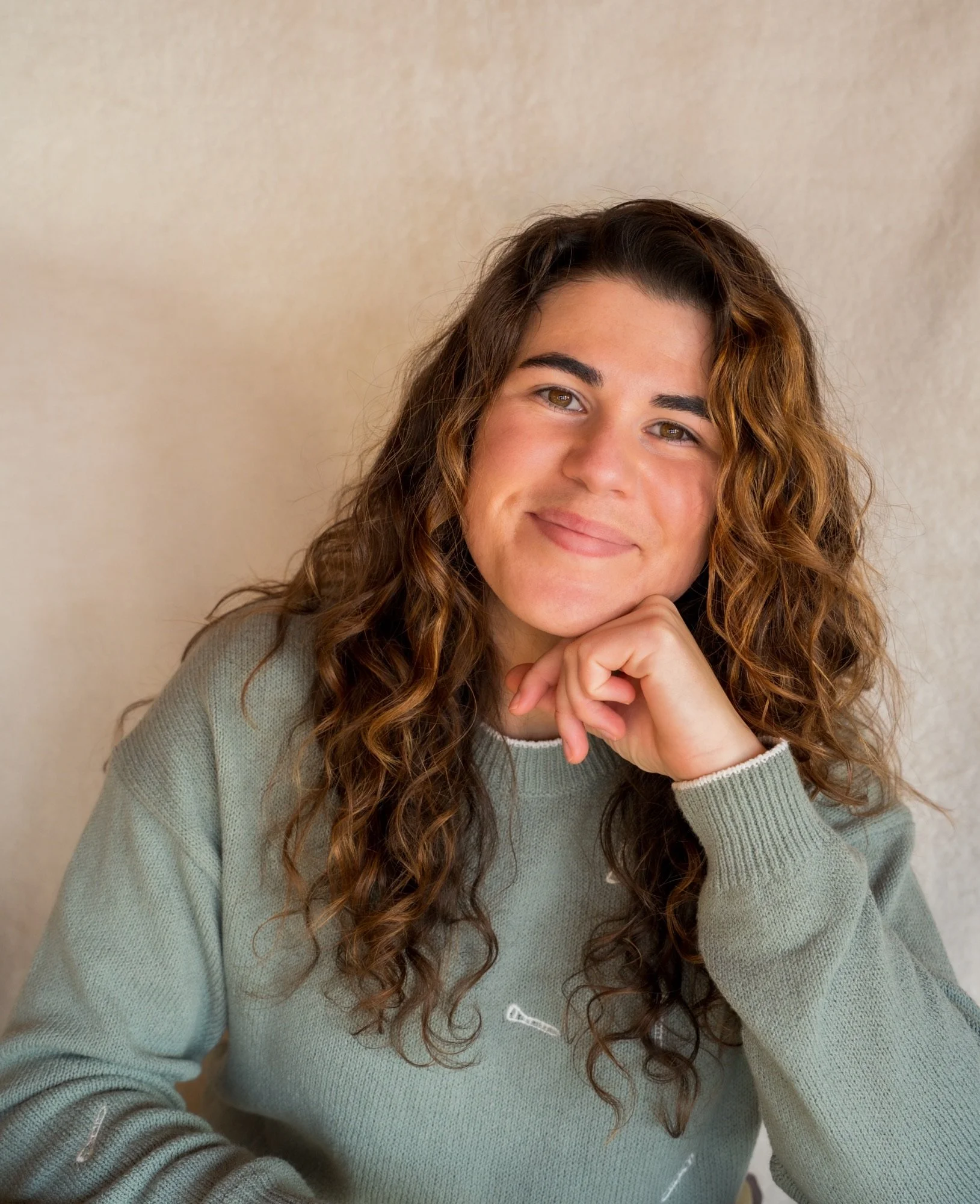 Alayna Eldred smiles at the camera with her hand on her chin