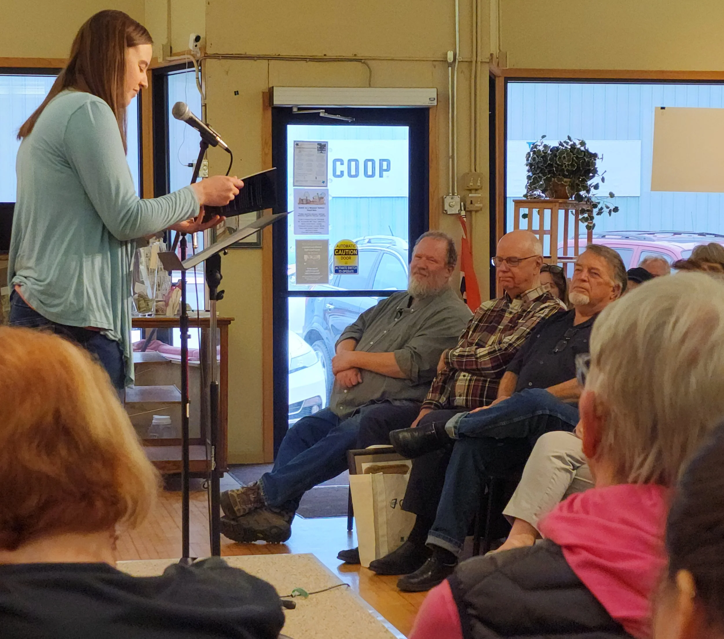 A woman is shown reading poetry to a group