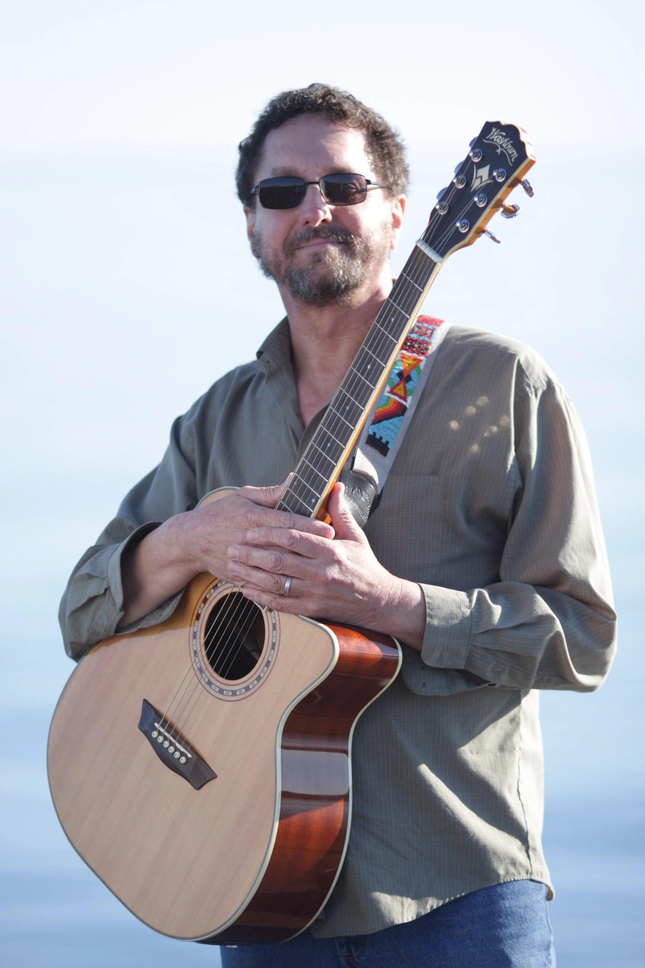 Dave Cofell stands outdoors holding a guitar
