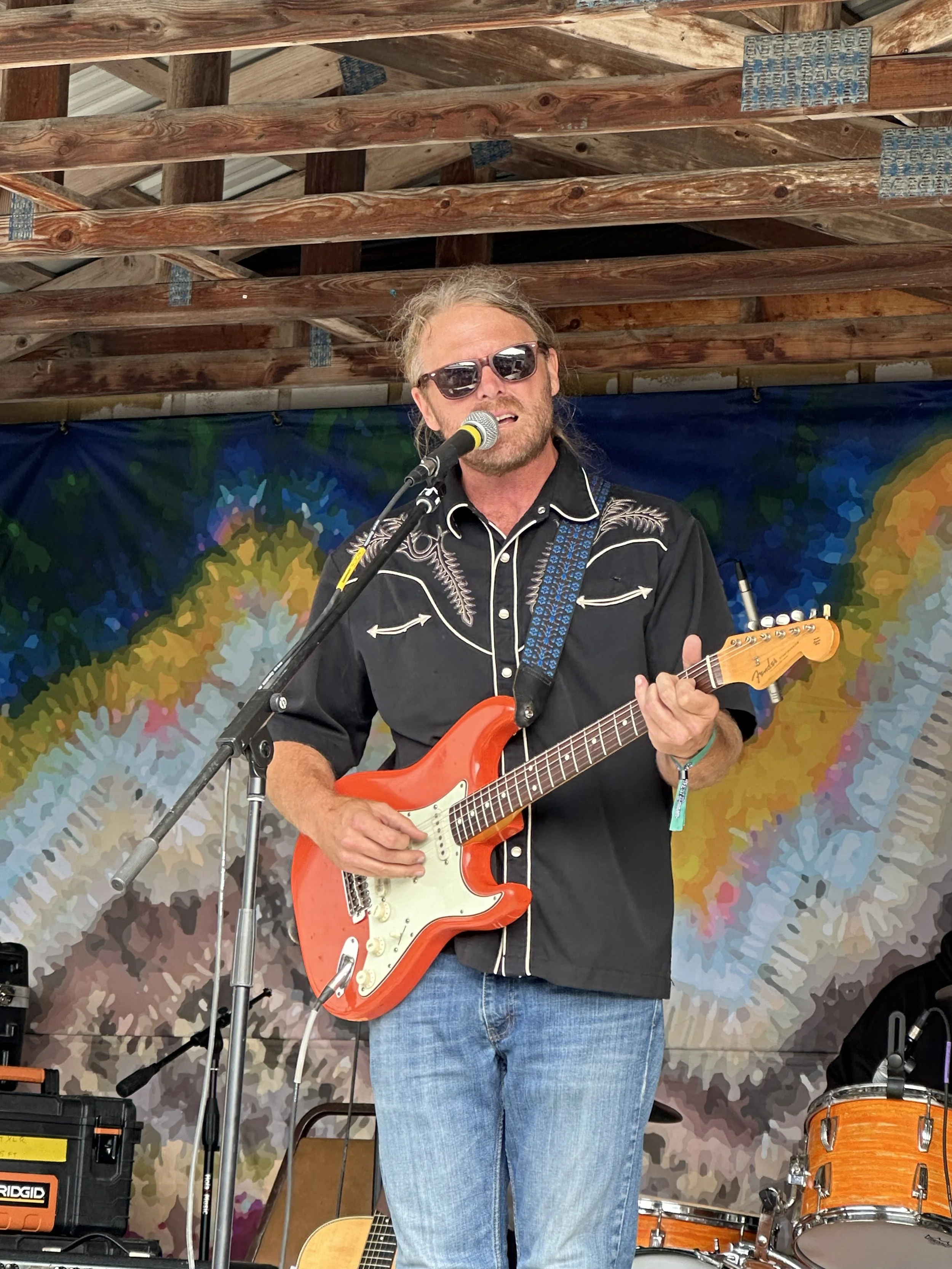 Robb Justice stands on a stage playing a guitar
