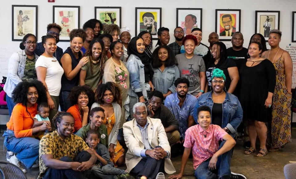 A photo of a group of people sitting and standing next to each other posing for a picture.&nbsp;