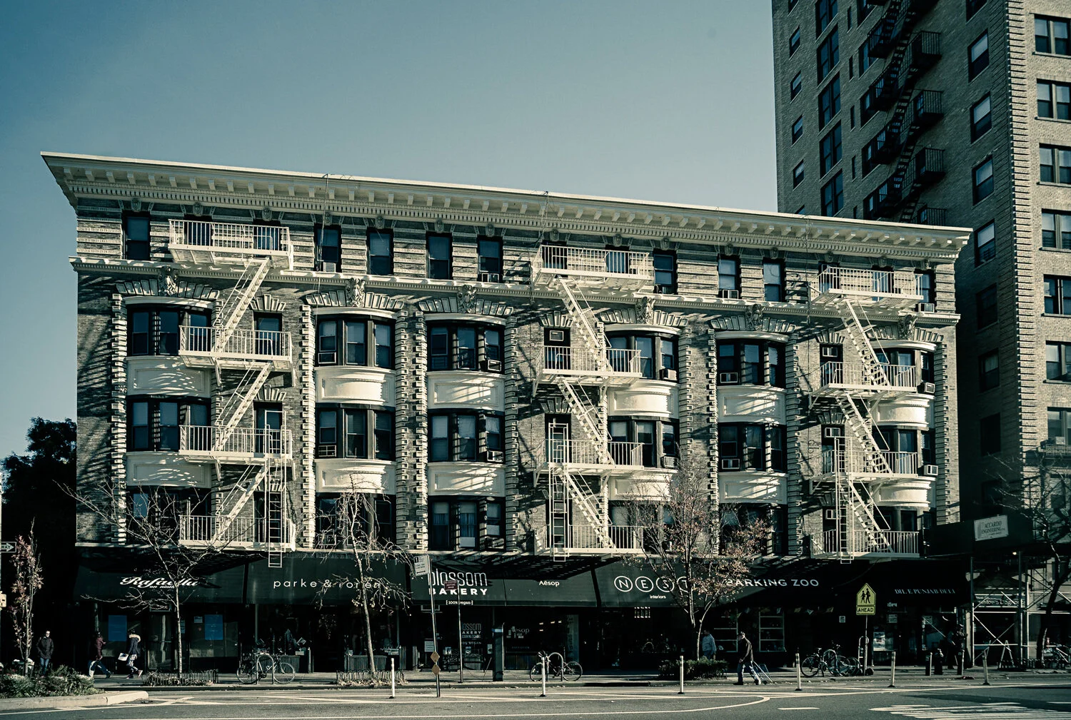 Historic 1920s apartment building with ornate architecture and fire escapes in a city setting.