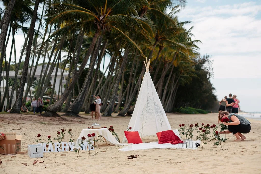 Cairns beach proposal setup with candles and roses at sunset