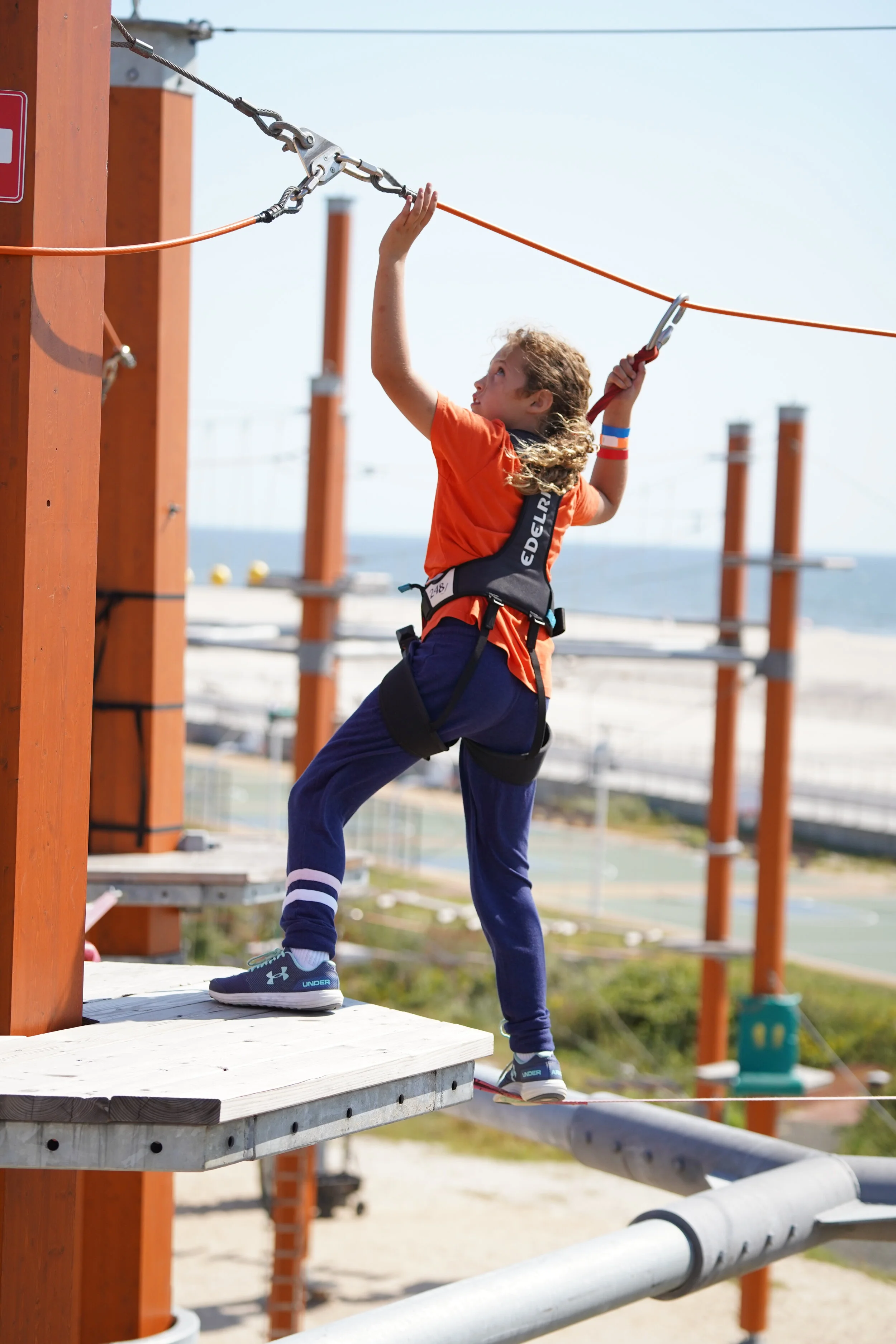Young child climbing through the Red level of the Classic Adventure Course at WildPlay outdoor adventure park.