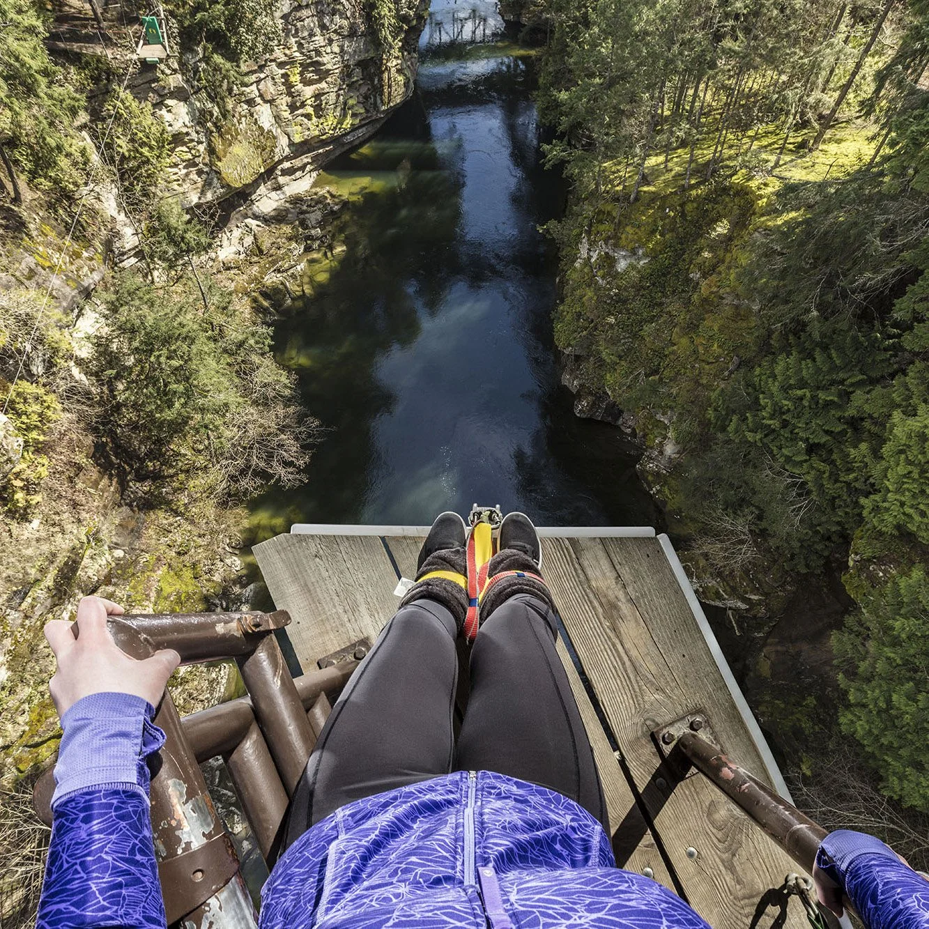Guest standing on bungy jump platform facing the Nanaimo River about to bungy jump 150ft down.