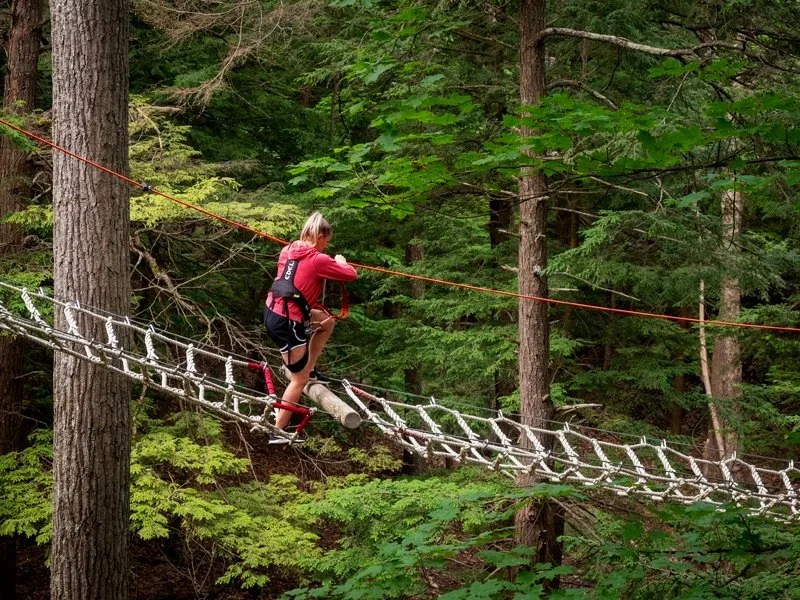 A guest walking across the adventure ropes course at WildPlay in Thacher State Park in Albany, New York.