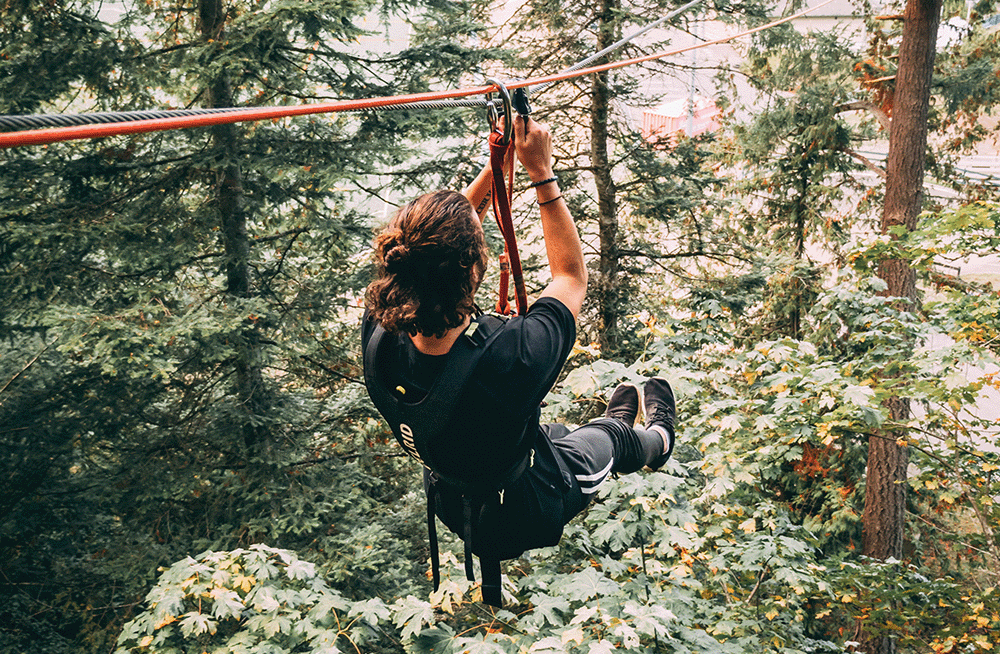 Man ziplining through the forest at WildPlay Victoria in British Columbia.