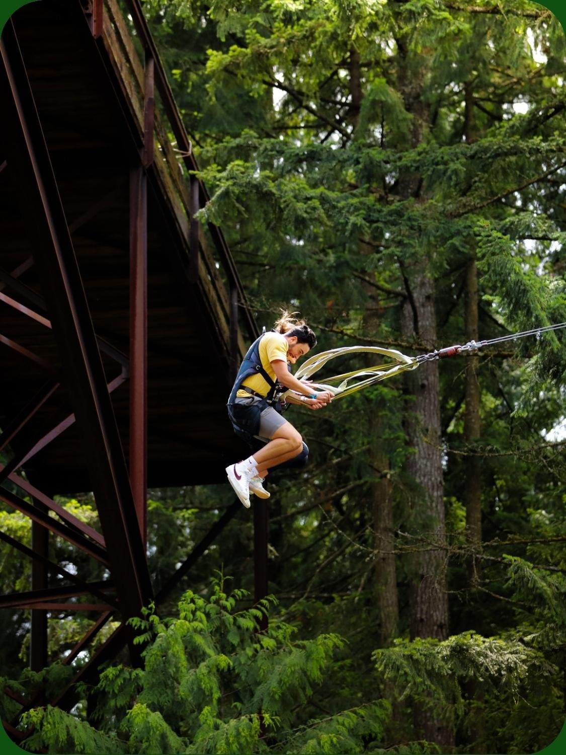 Two guests swinging off the bridge overlooking the Nanaimo River at WildPlay Nanaimo, British Columbia. 