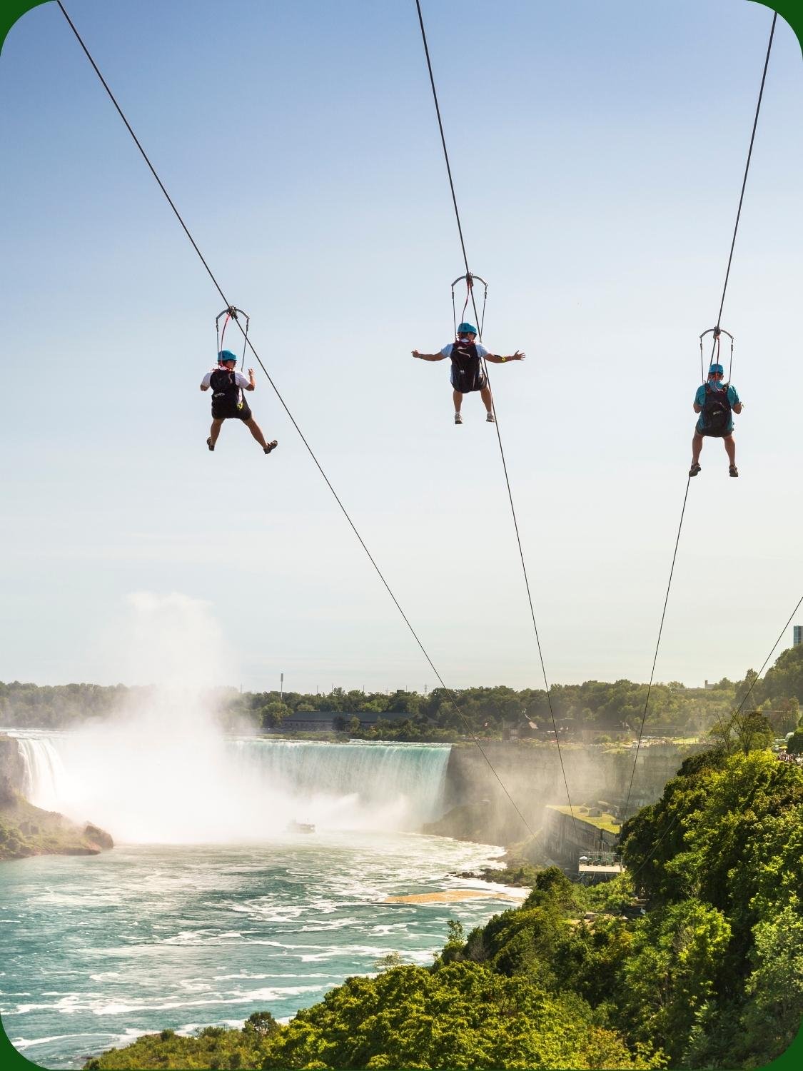 Group of people ziplining over the water at WildPlay Zipline to the Falls Niagara Falls.