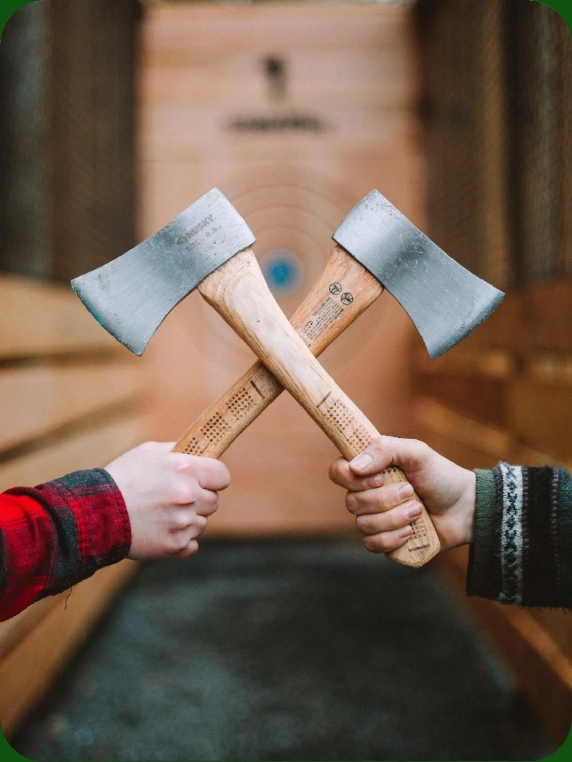Two guests holding axes and preparing for axe throwing.