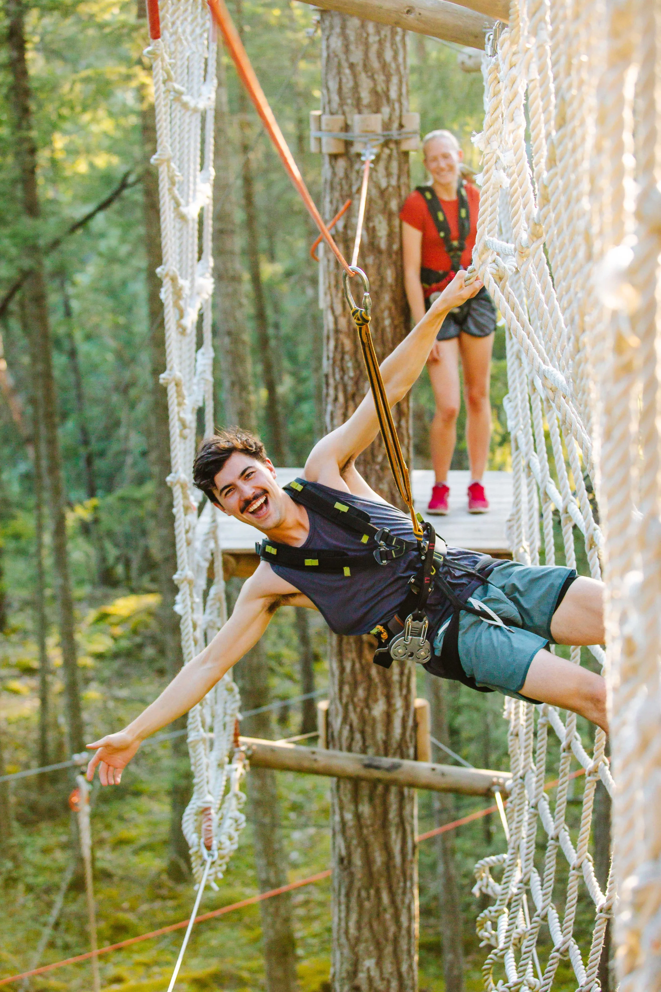 A man hanging off of the ropes net on the adventure courses at WildPlay in Maple Ridge, British Columbia.