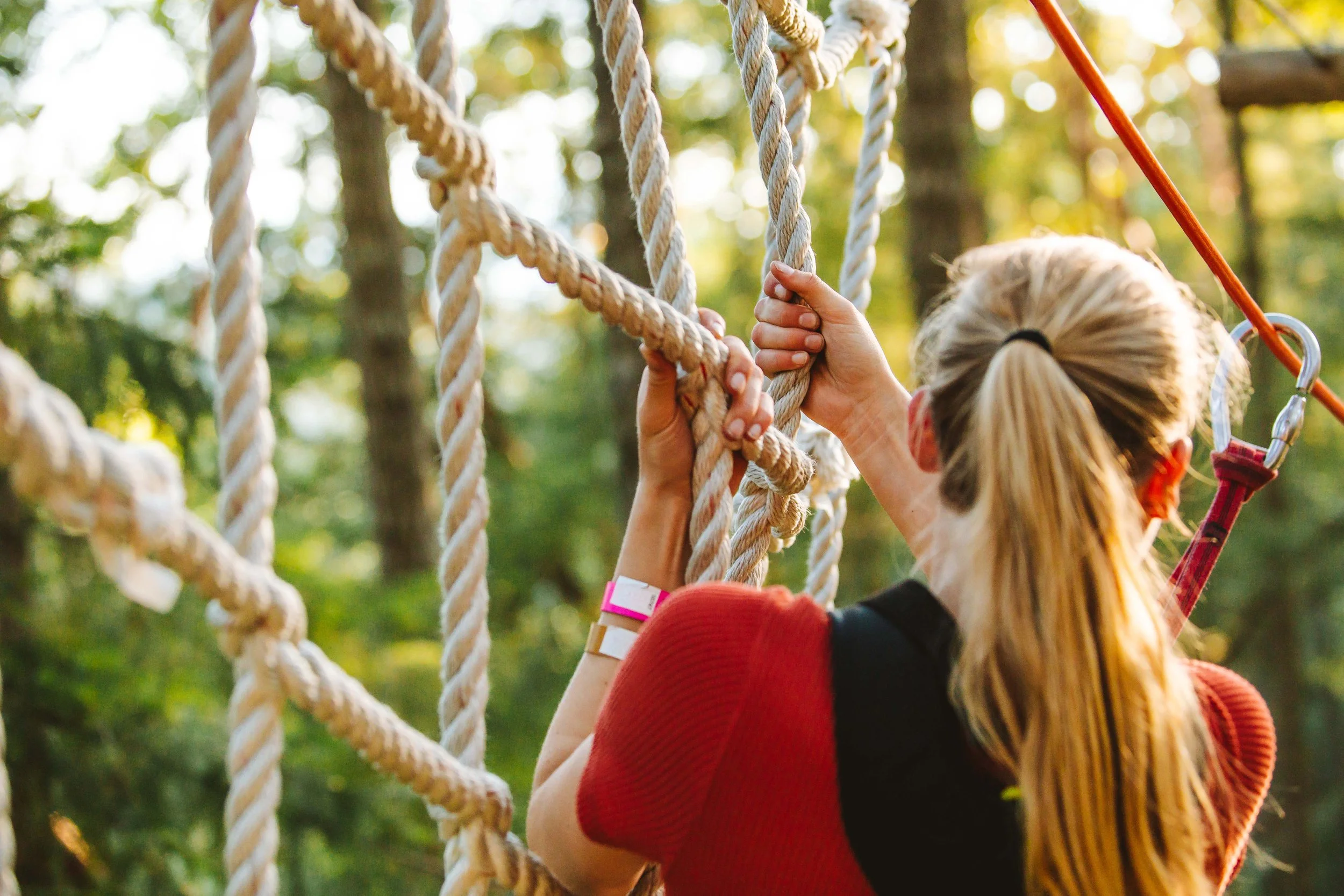 A girl climbing through treetop ropes courses at WildPlay, outdoor adventure park in British Columbia. 