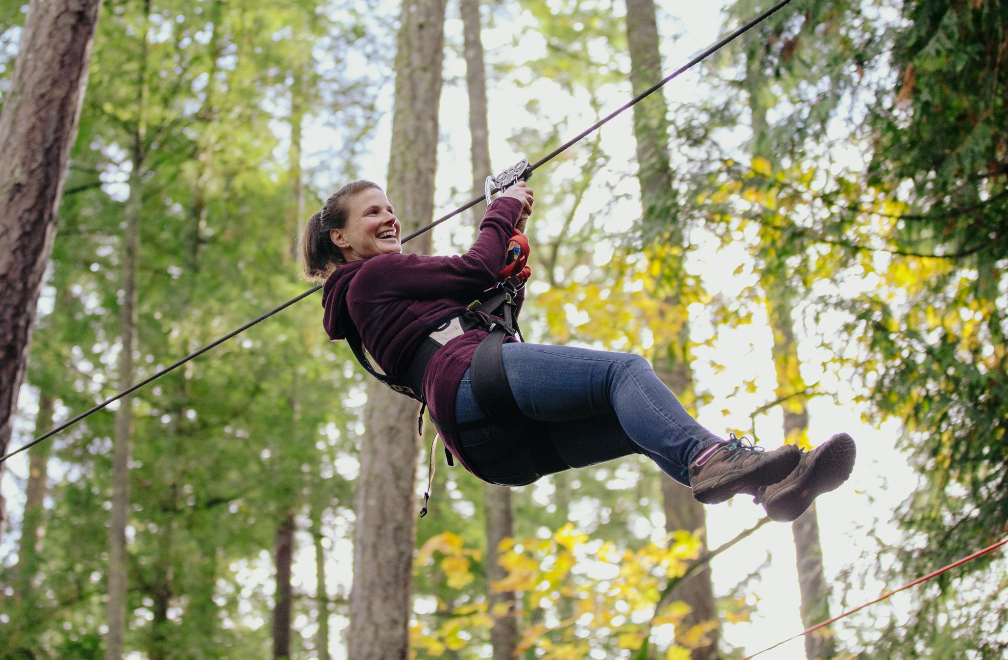 women ziplining through the trees at outdoor adventure park