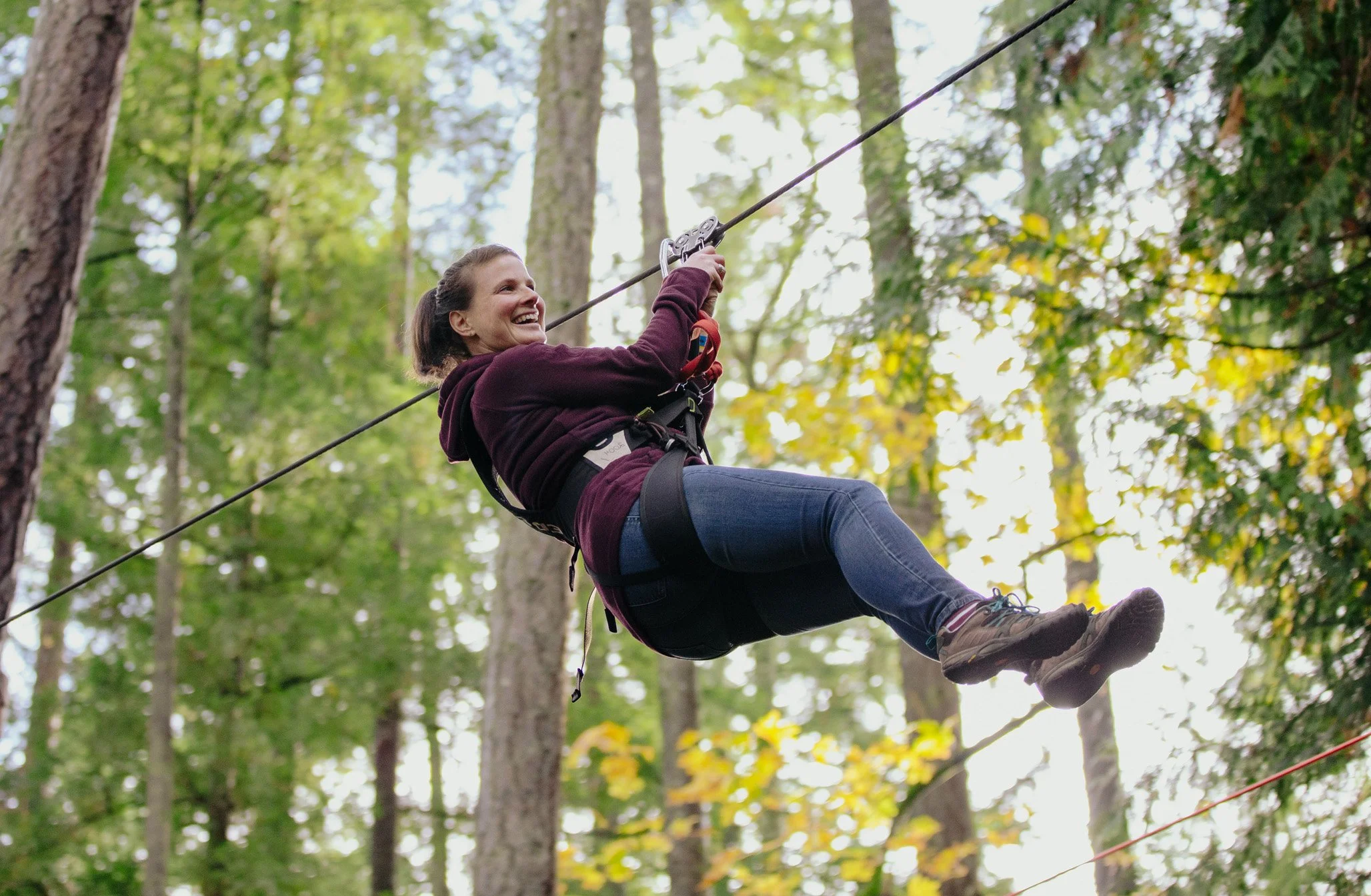 Woman ziplining through the trees at outdoor adventure park in Victoria British Columbia.