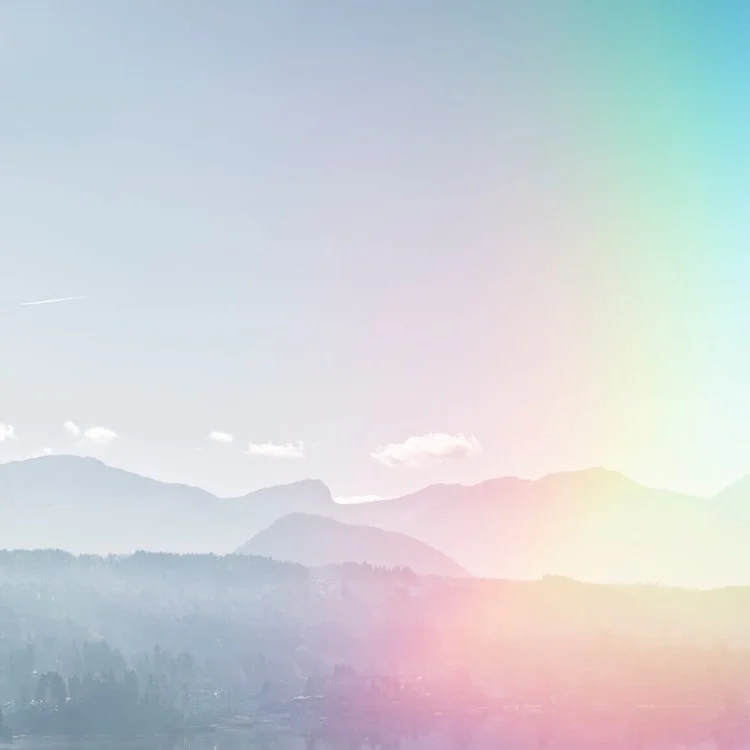 Blurred mountain landscape with a faint rainbow in the sky.