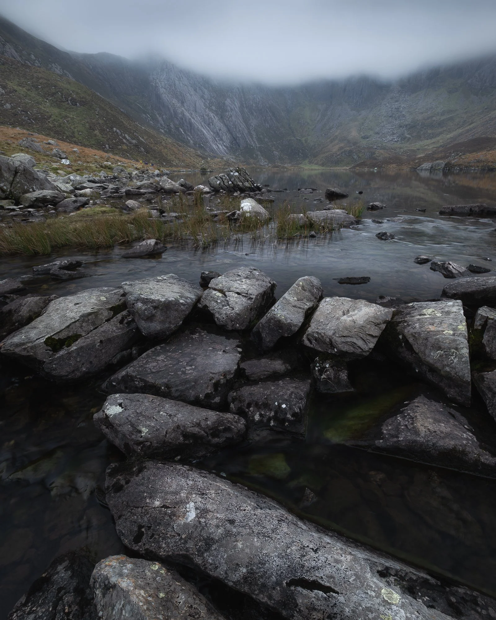 A photo of Llyn Idwal with rocks in the foreground looking towards the Devil's Kitchen in the Ogwen Valley, Snowdonia taken by Trevor Sherwin