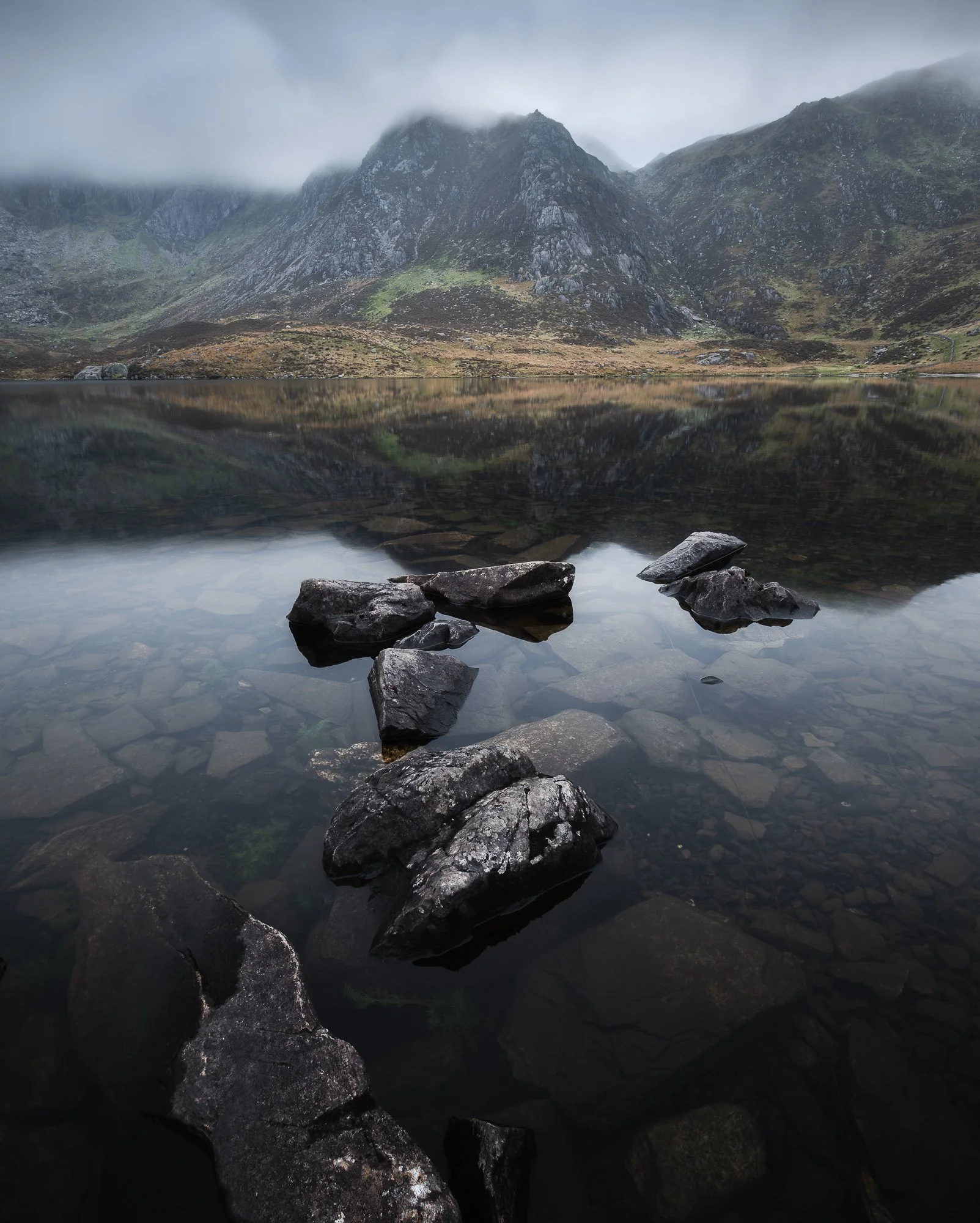 A photo of some partly submerged stones that lead the eye towards Llyn Idwal and up to Y Garn in the background. Taken in Snowdonia by Trevor Sherwin