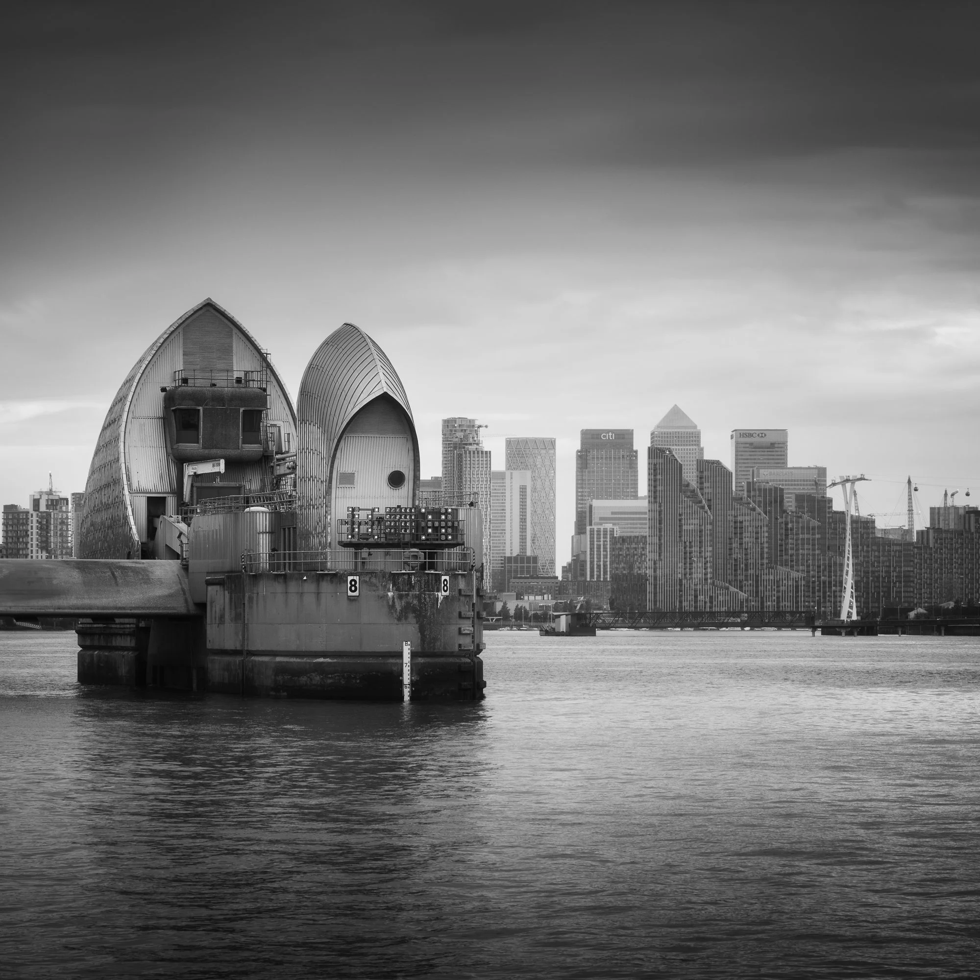 Thames Barrier structure standing in the River Thames with the Isle of Dogs skyline in the background, London