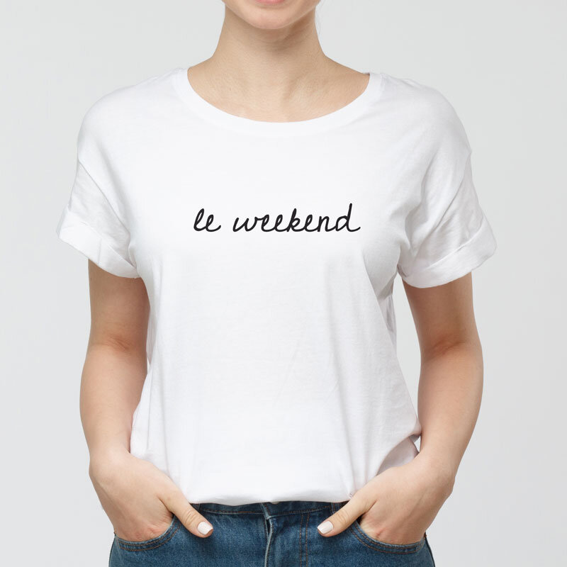 Person wearing a white t-shirt with "le weekend" printed in black cursive font.