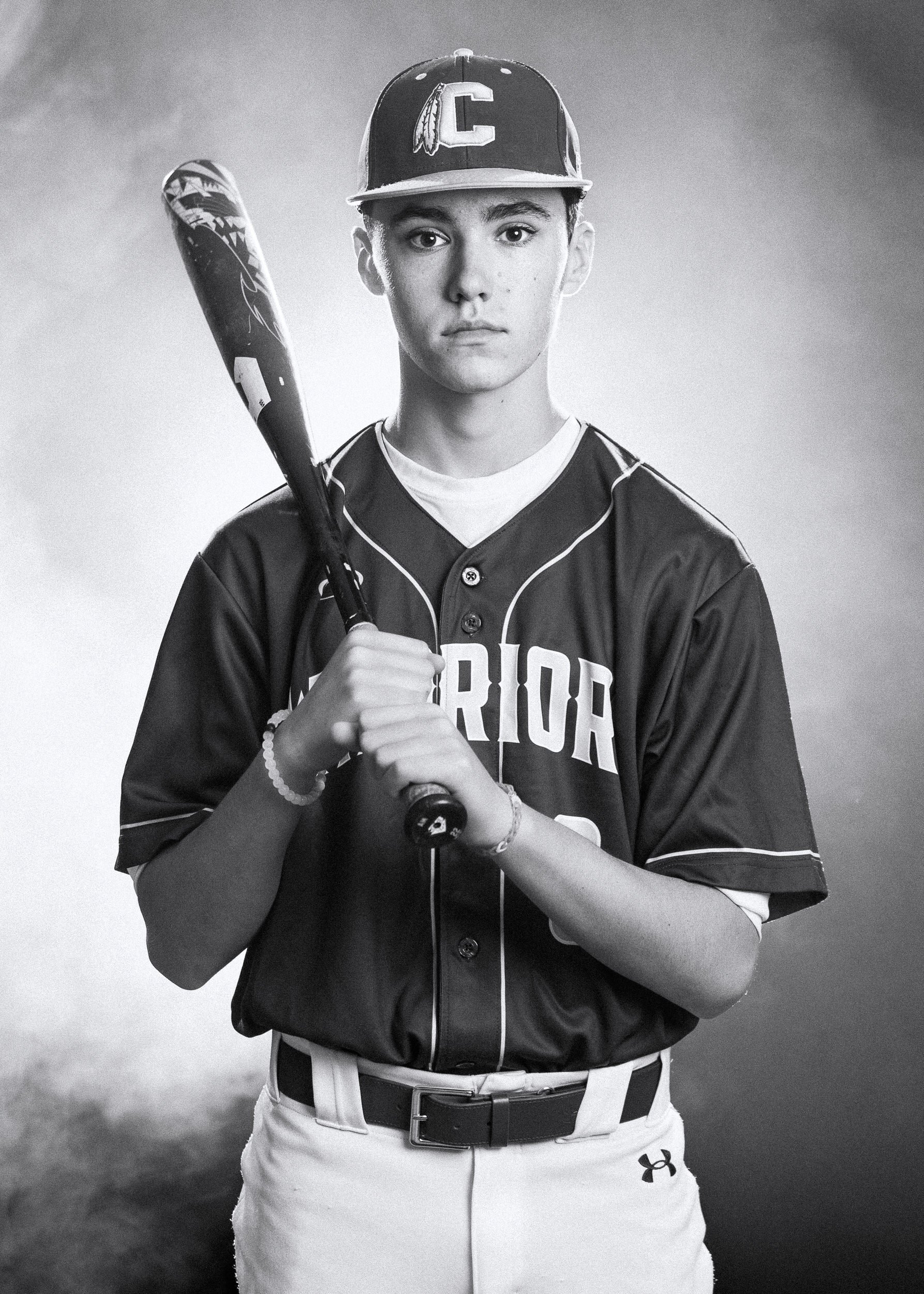 Young baseball player in uniform holding a bat, monochrome photo.