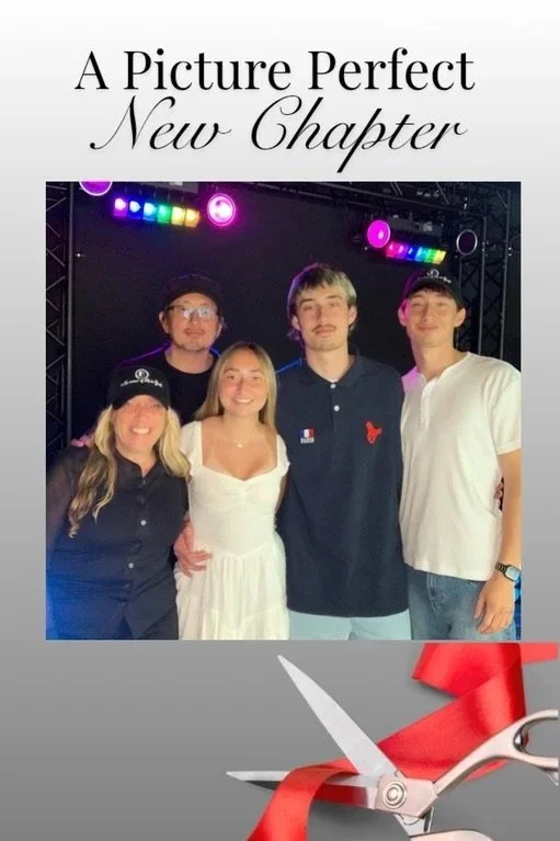 Group of five young adults posing for a photo at a celebration event called "A Picture Perfect New Chapter" with colorful stage lights in the background and a graphic of scissors cutting a red ribbon at the bottom.