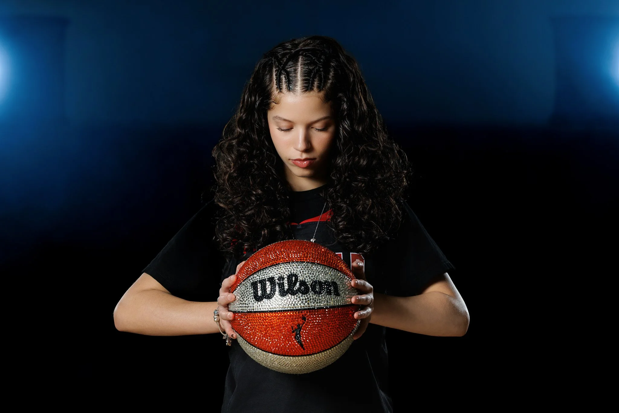 Young woman with curly hair holding a decorated Wilson basketball.