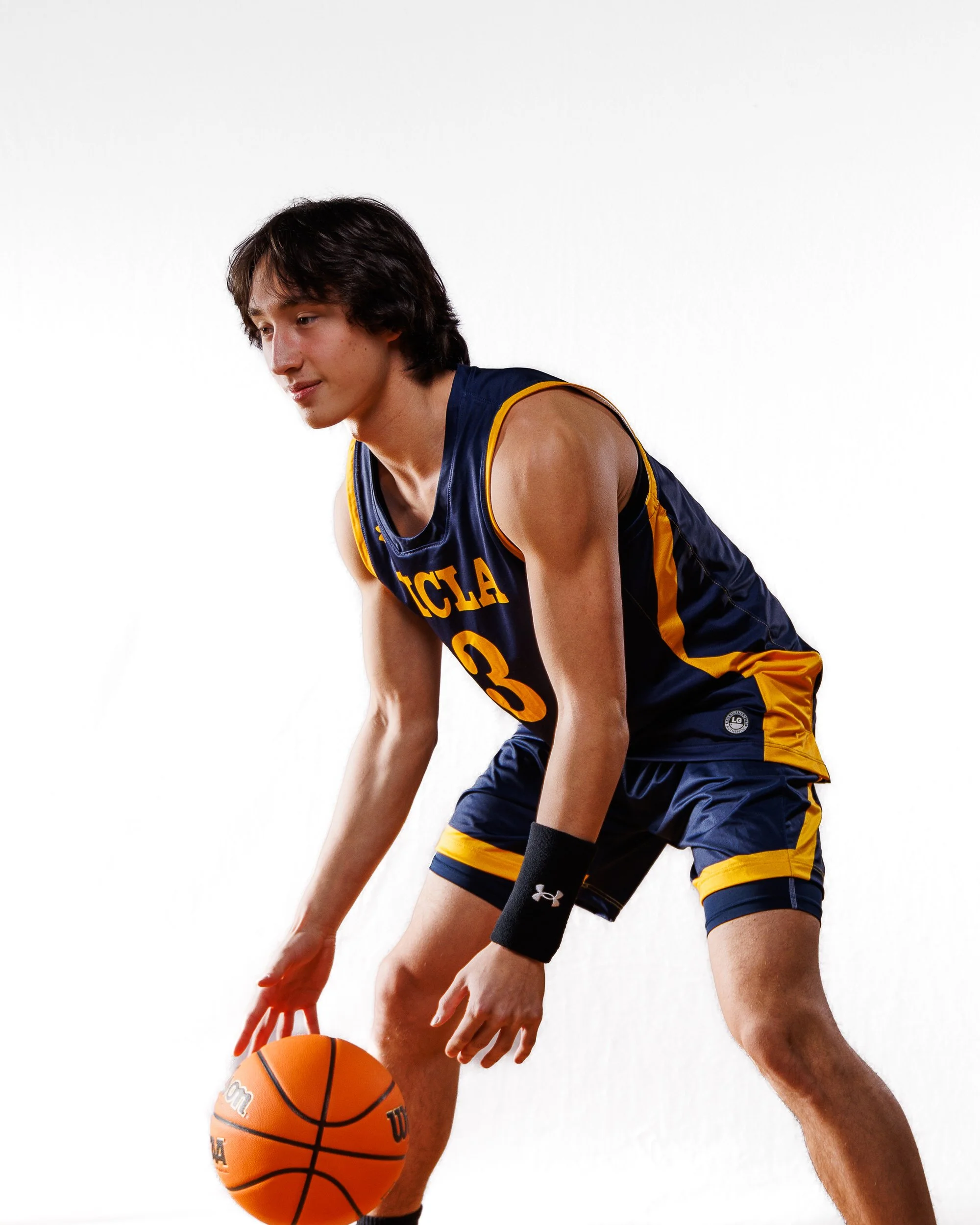Basketball player in UCLA jersey dribbling a basketball