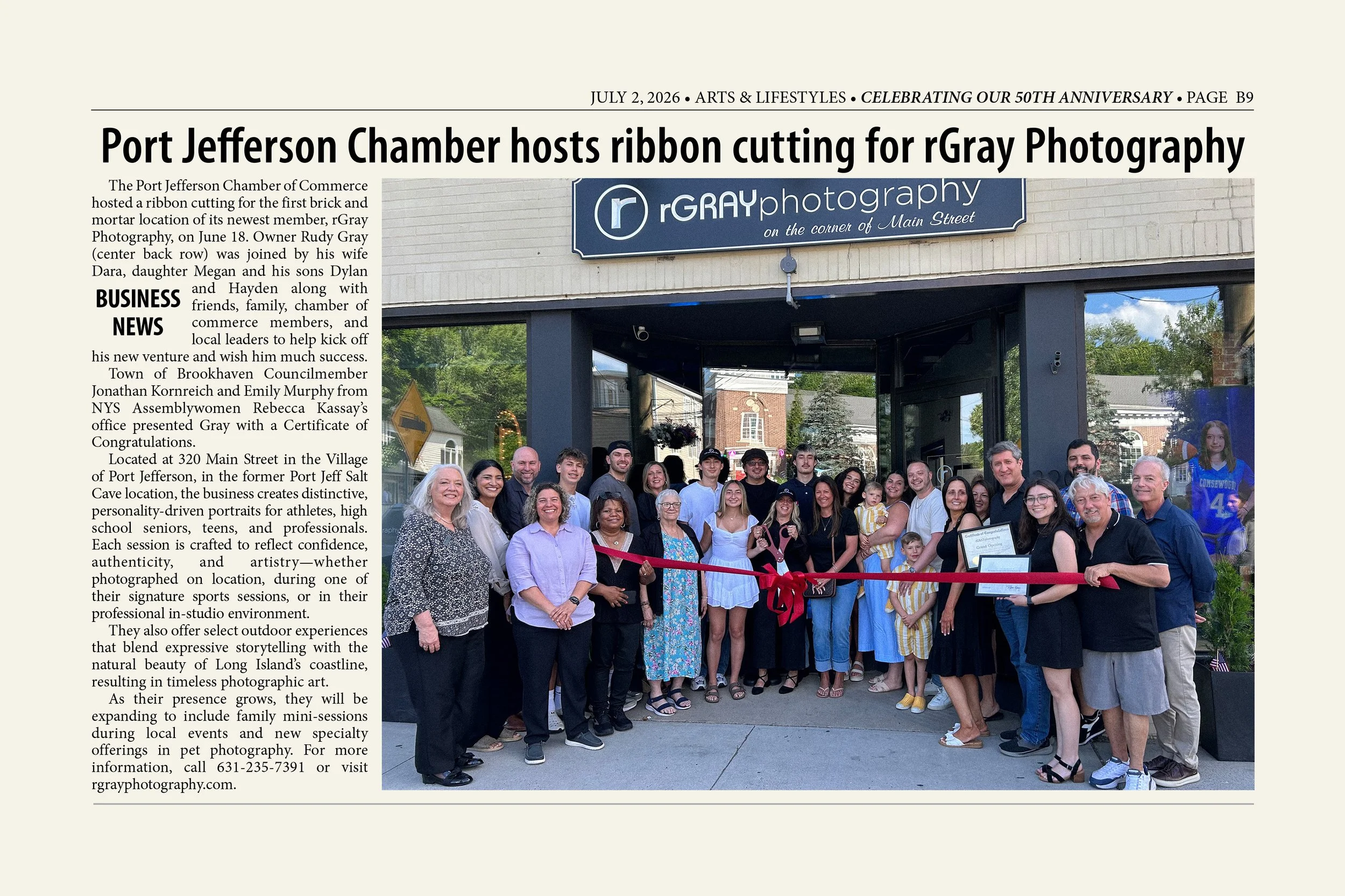 Group of people posing outside the rGray Photography studio during a ribbon cutting event, with a sign displaying the studio's name and slogan above the entrance.