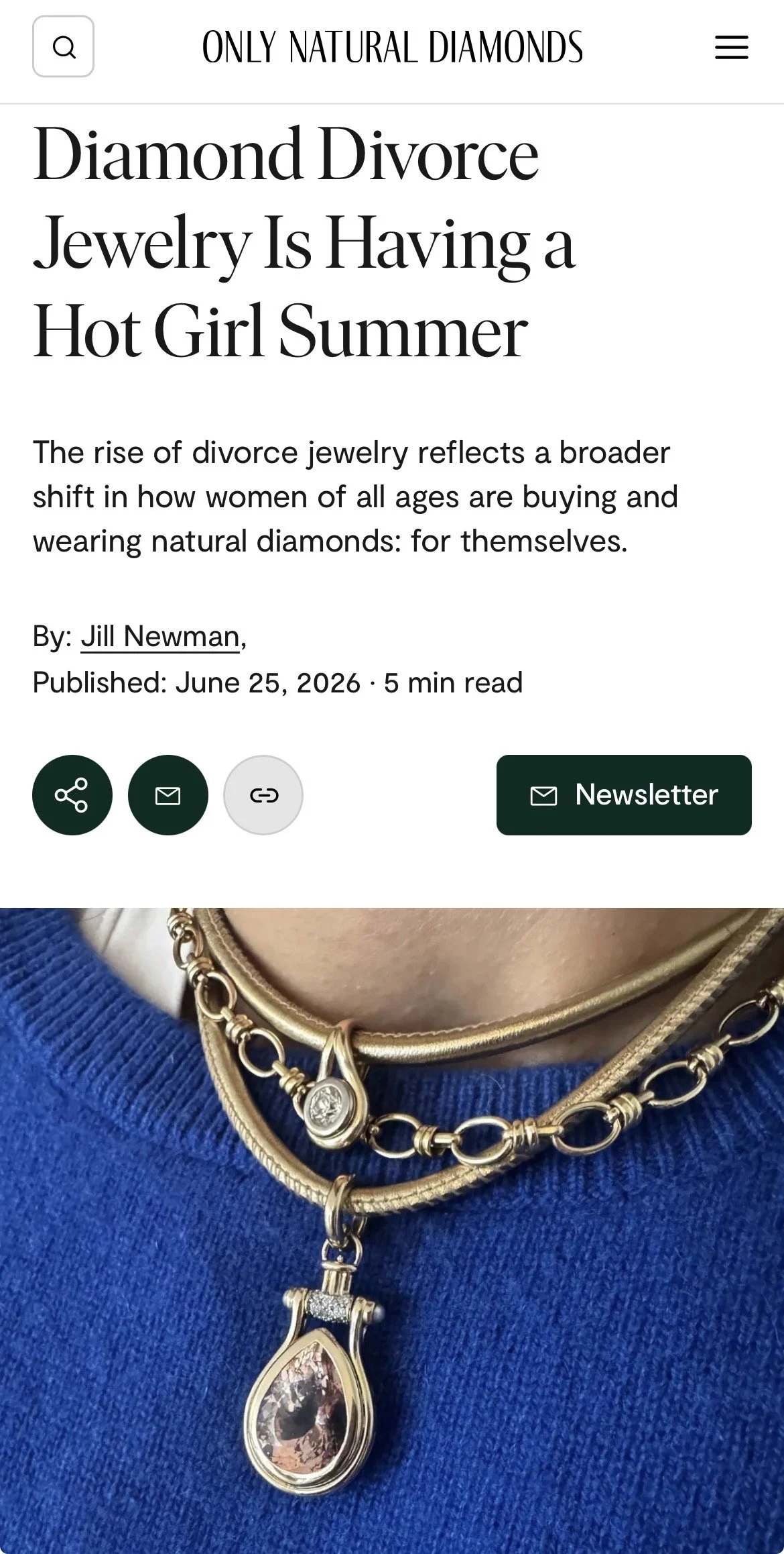 Close-up of layered gold necklaces with a large teardrop-shaped gemstone pendant, worn over a blue garment.