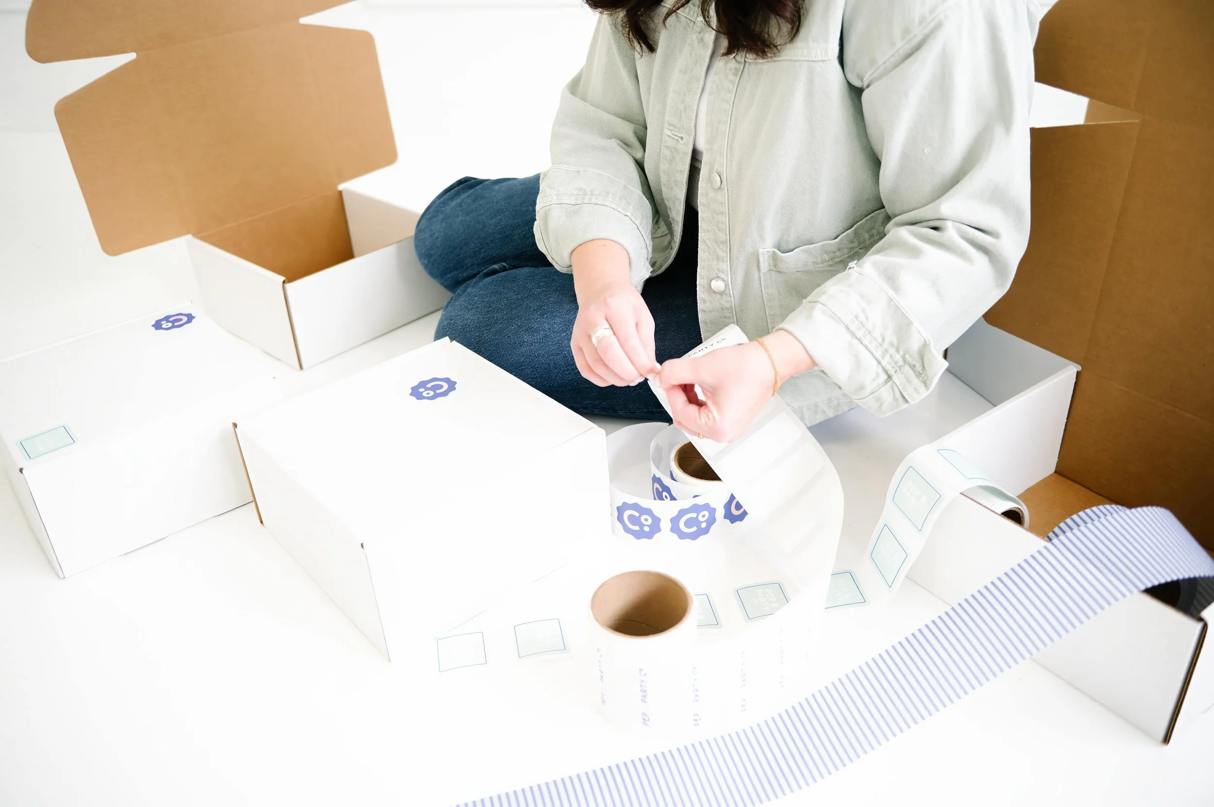 Annie Bradshaw packaging a custom gift box and applying branded stickers for Pep & Party Co. orders.