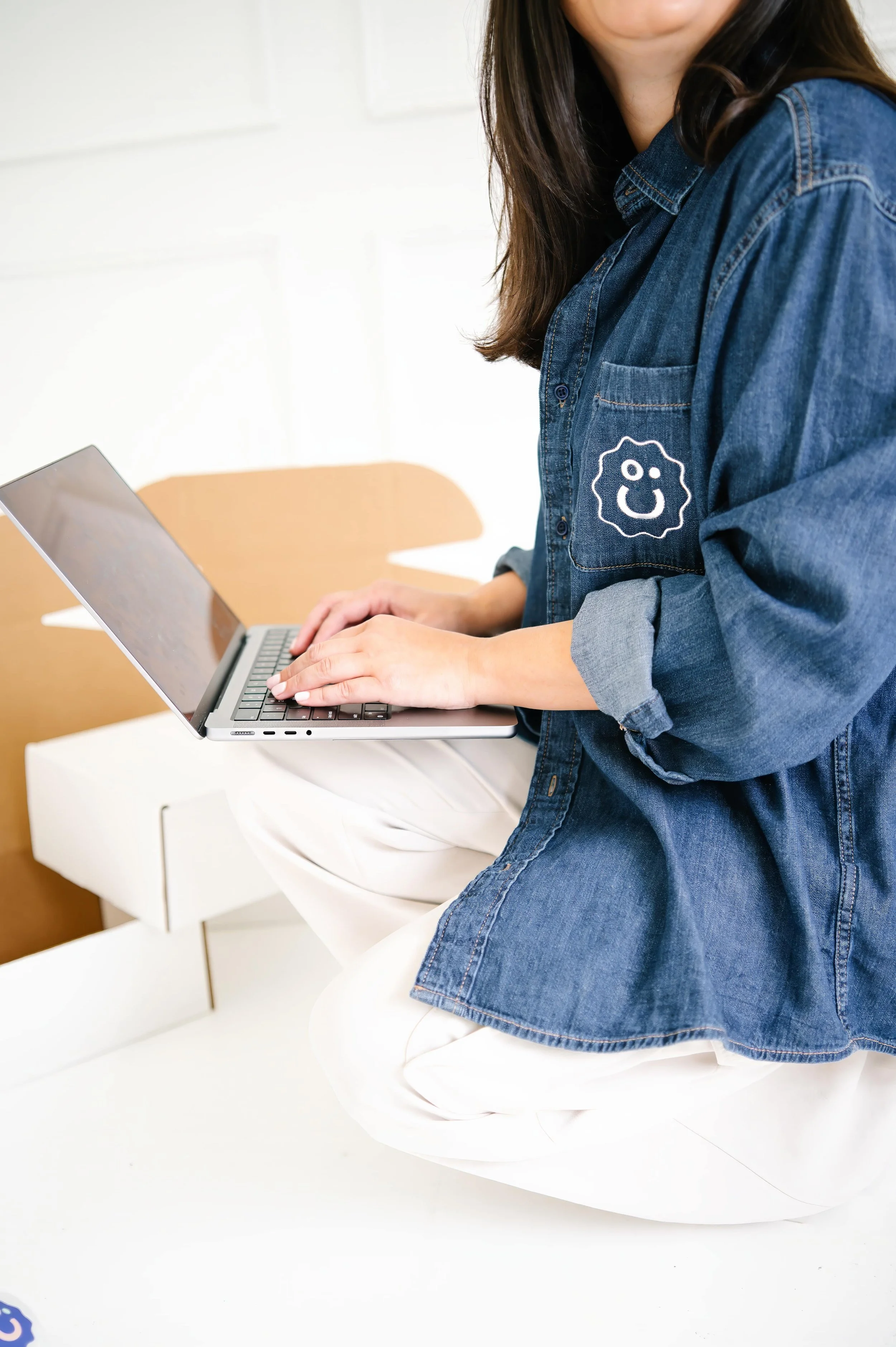 Annie Bradshaw managing gift orders on her computer while preparing personalized gift boxes.