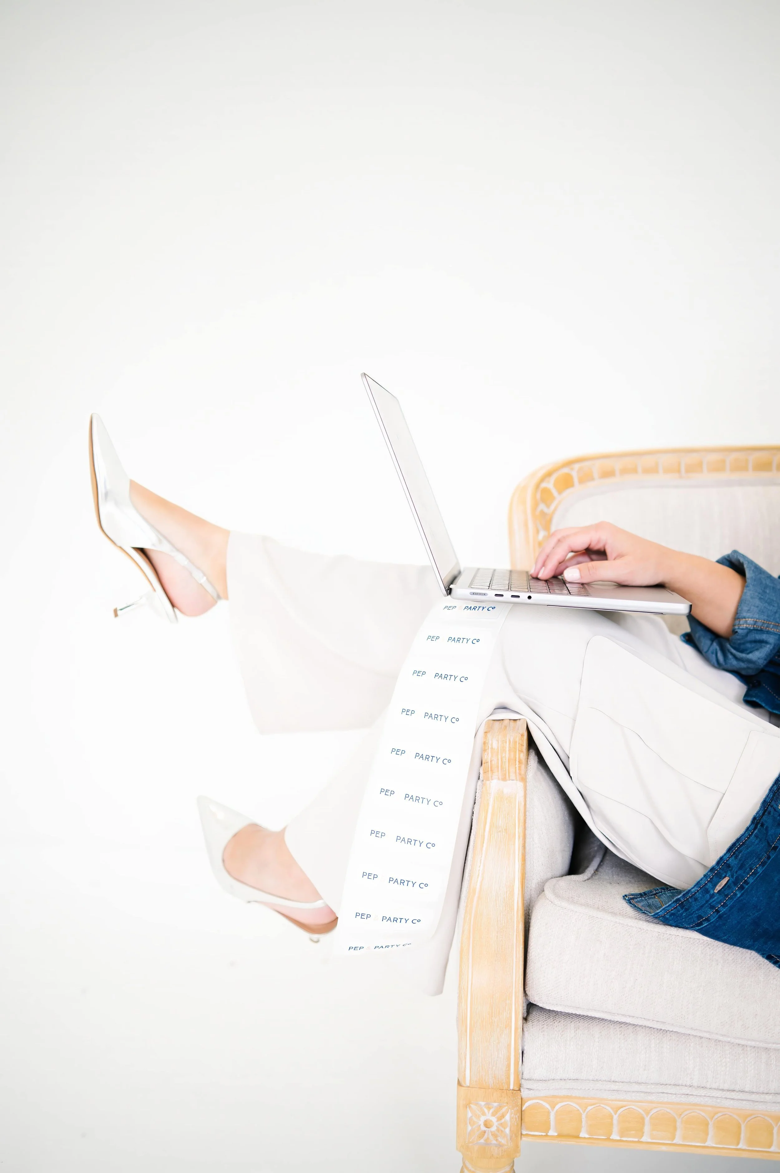 Annie Bradshaw working on a computer while sitting in a chair, creating custom gift box designs for Pep & Party Co.