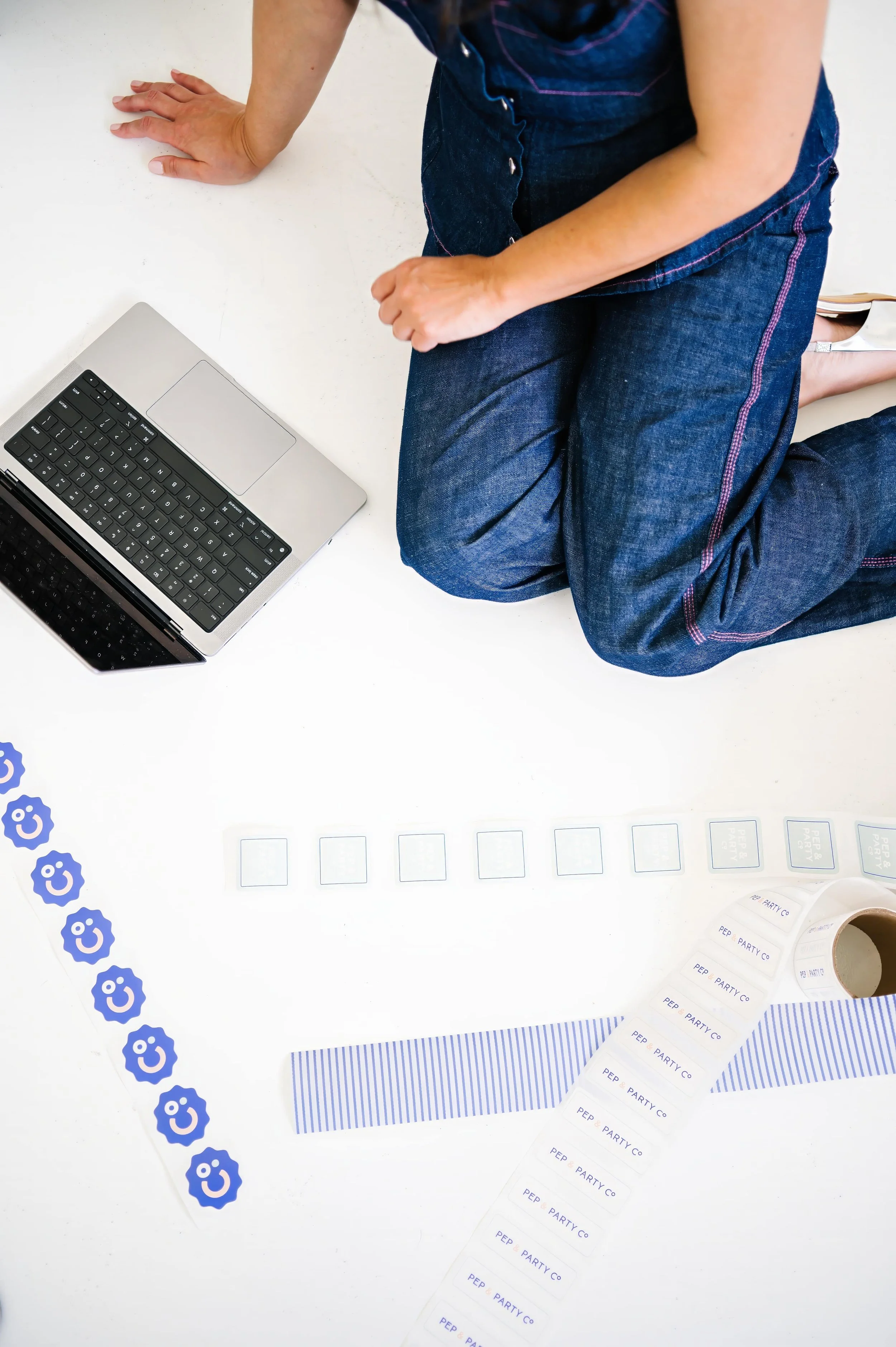 Annie Bradshaw working on a computer surrounded by creative assets and packaging materials while designing custom corporate gifts.