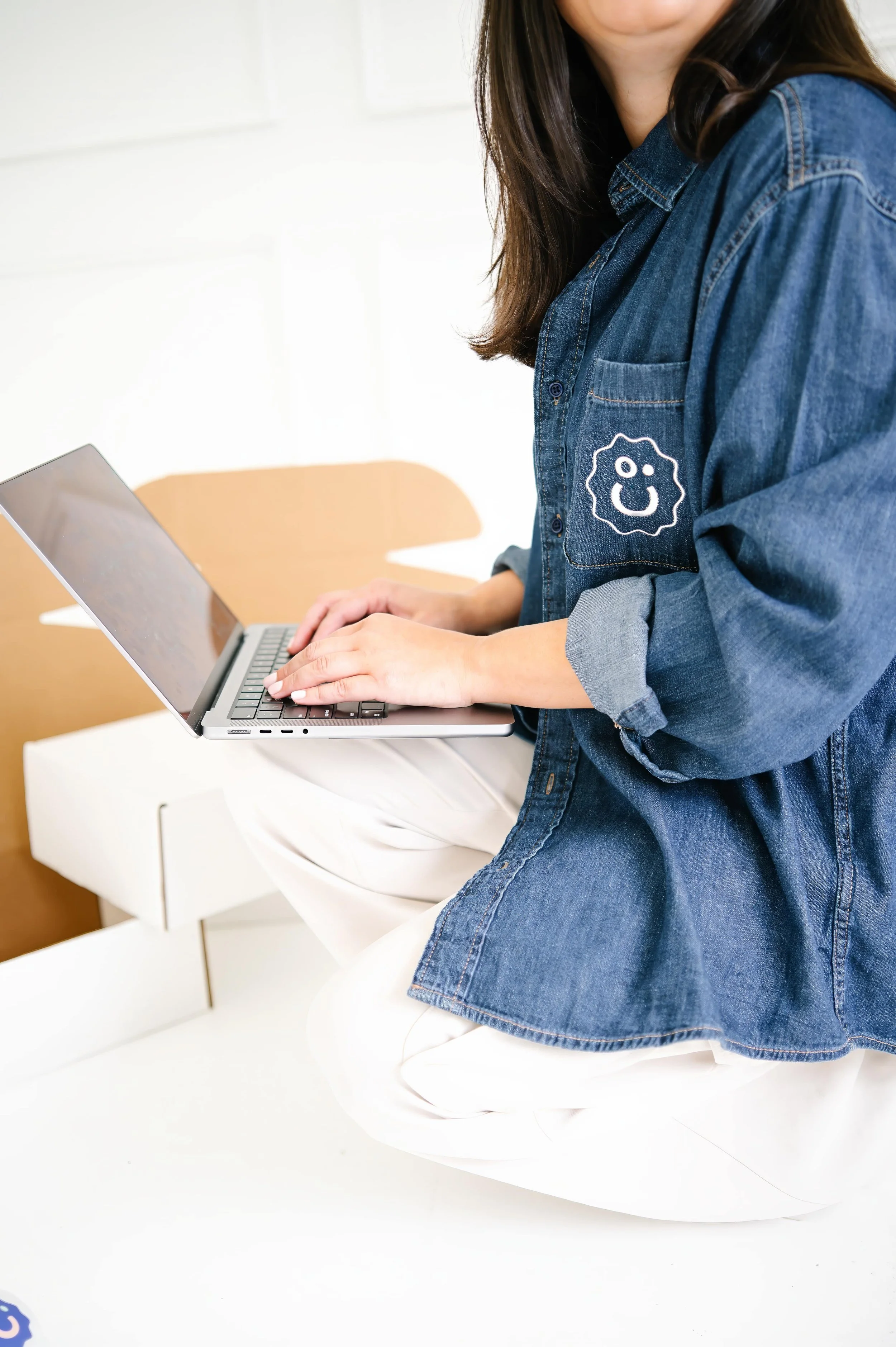 Annie Bradshaw squatting while typing on a computer and creating custom corporate gift boxes for Pep & Party Co.