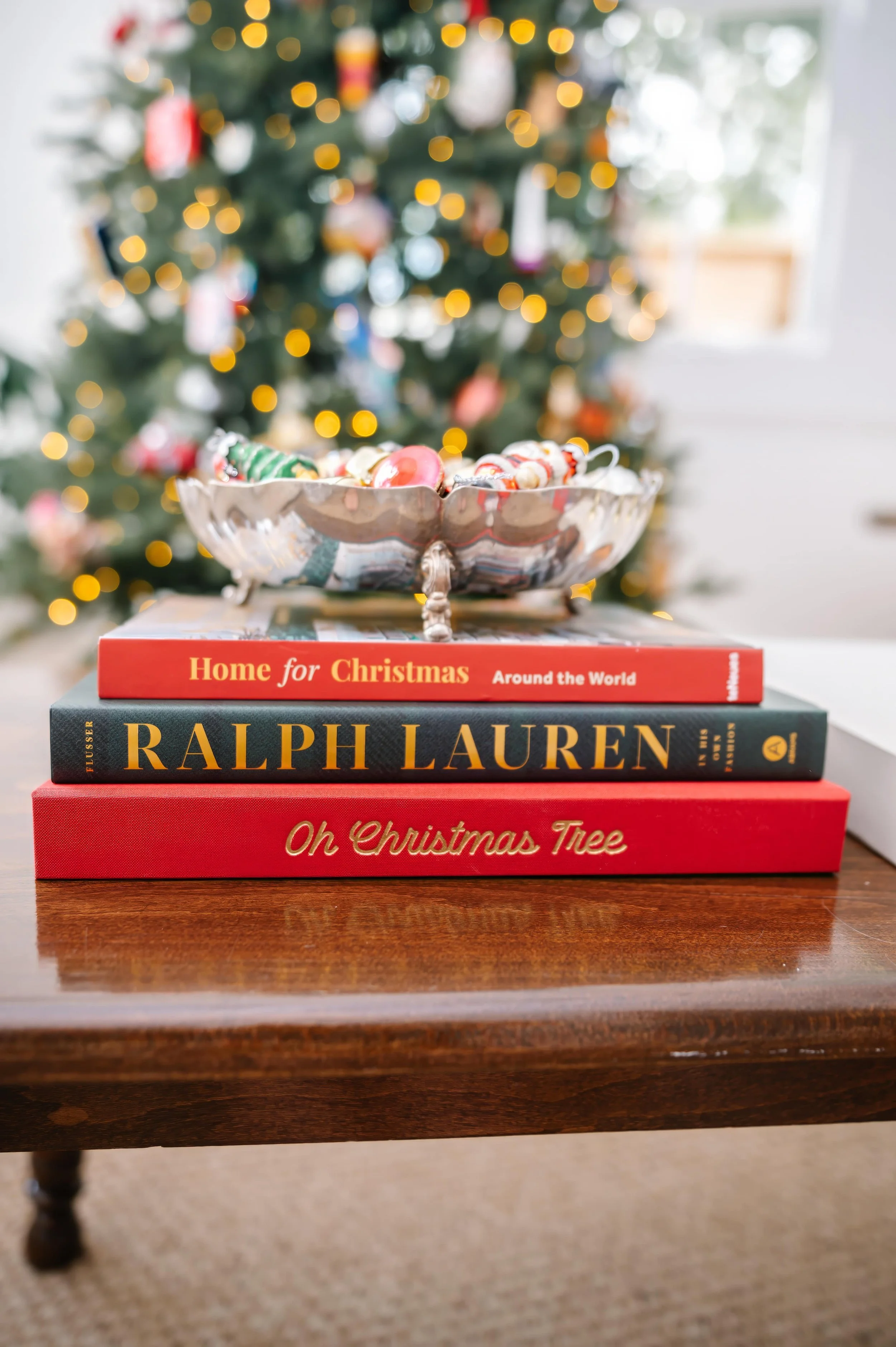 Christmas ornament memory book on a living room table with a Christmas tree in the background.