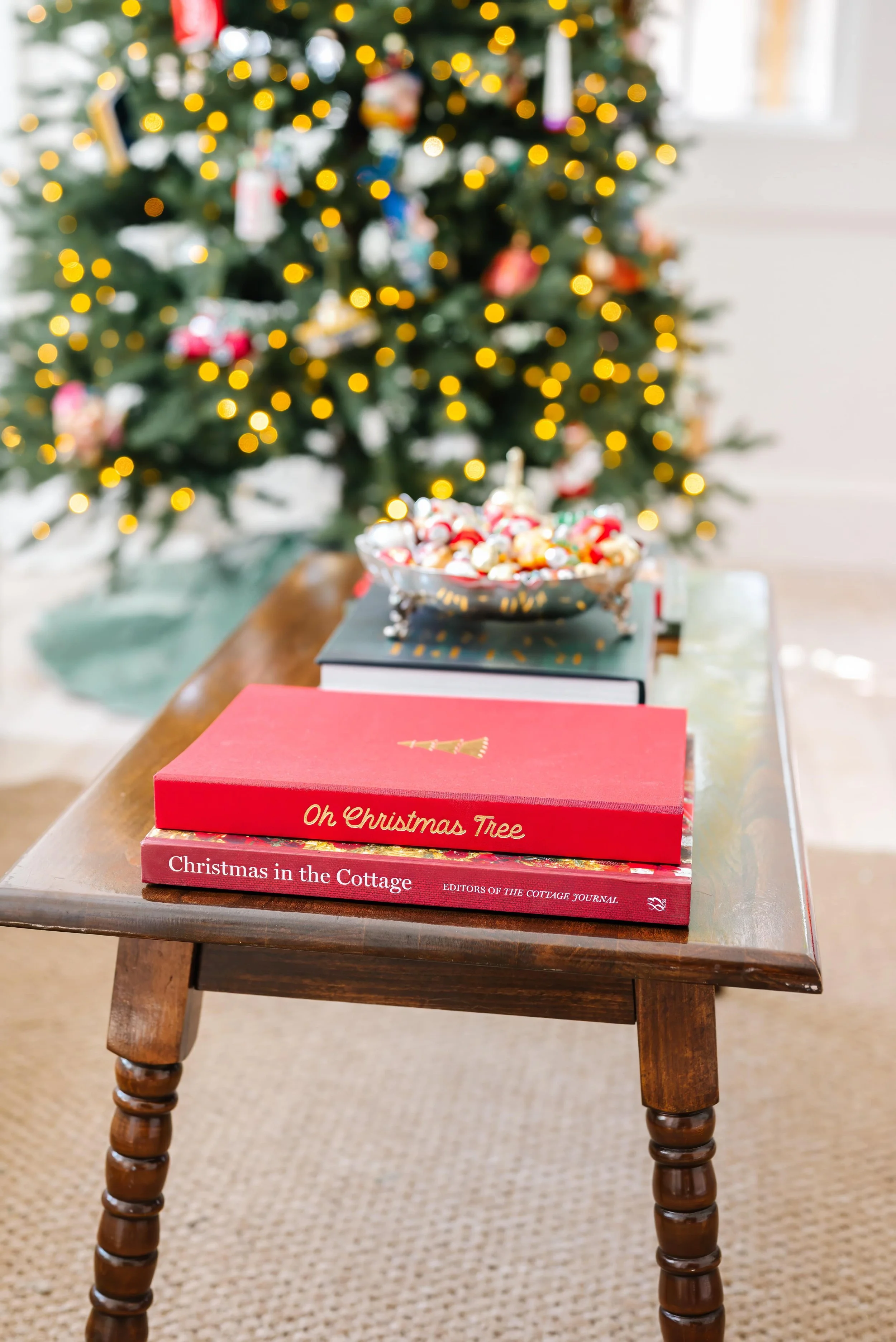 Christmas ornament memory book on a living room table with a Christmas tree in the background.